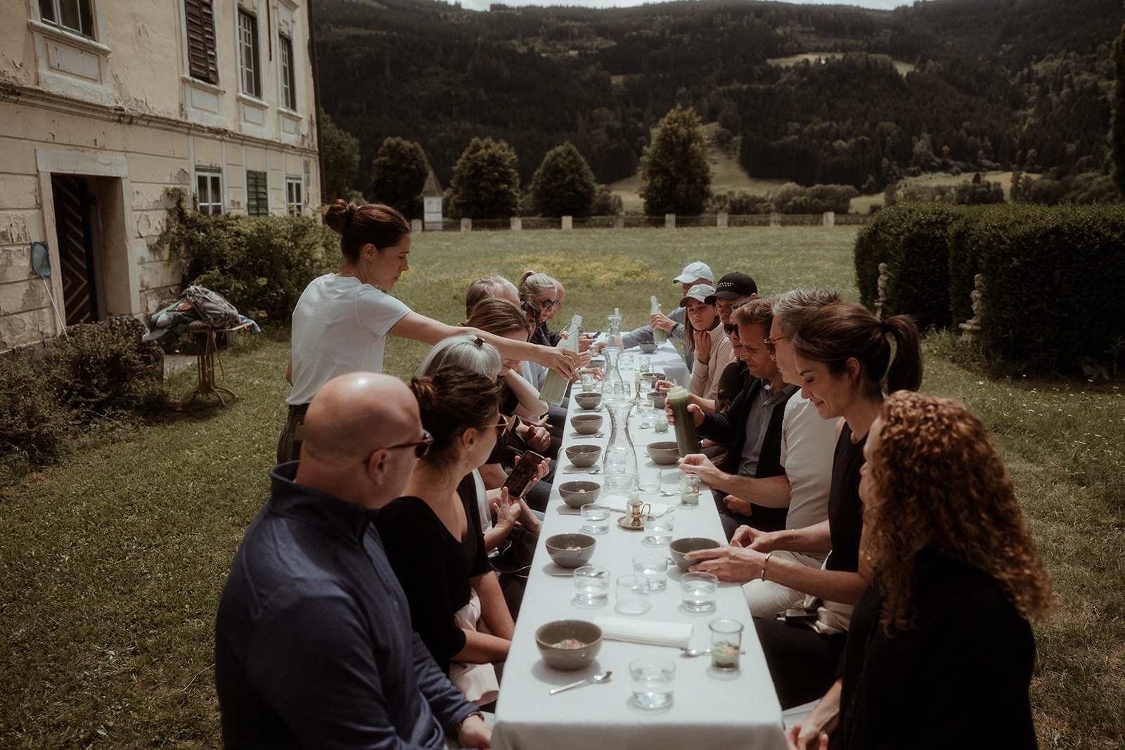 A long table set for dinner in the garden with guests seated