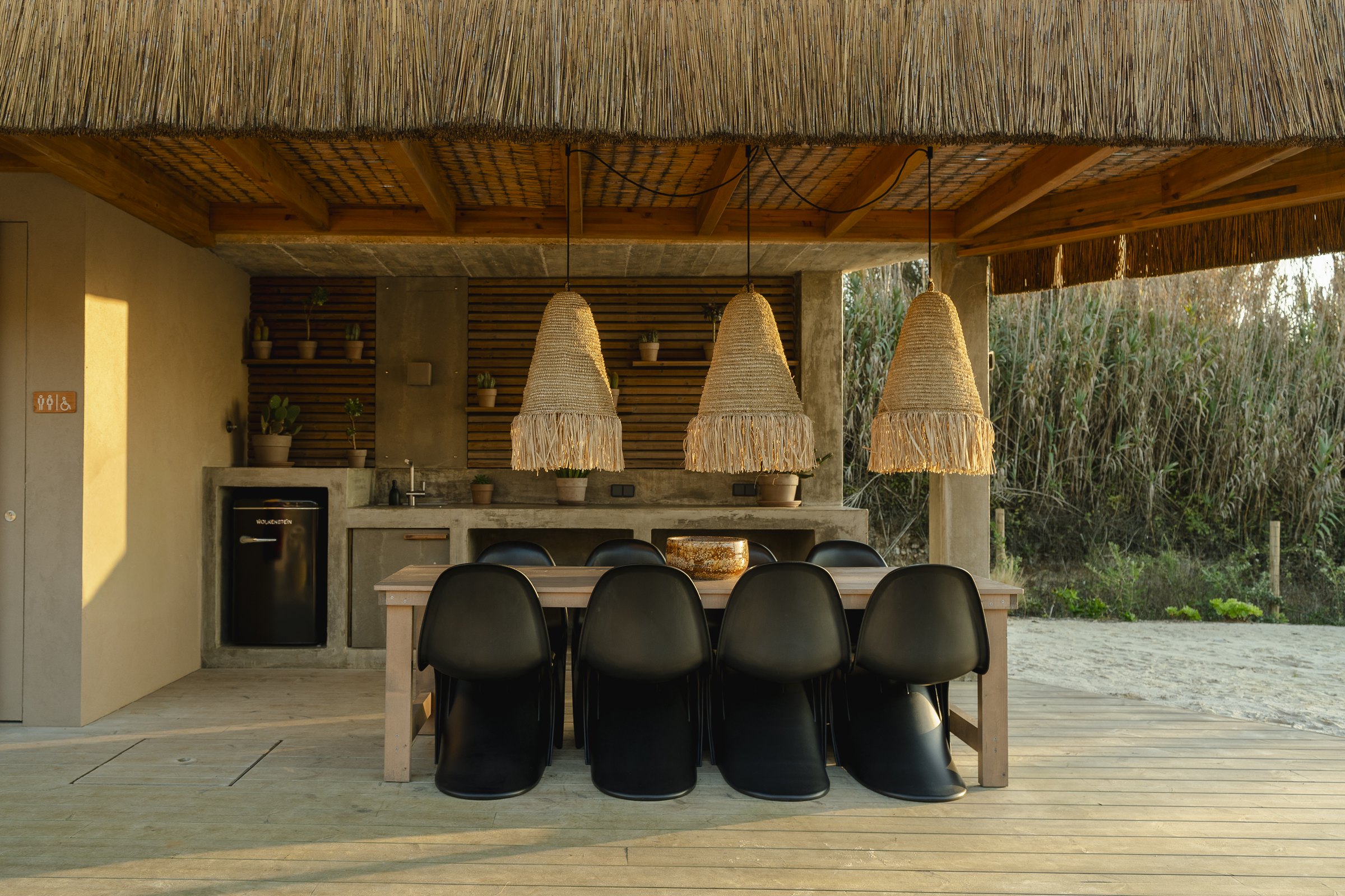 The open-air kitchen and dining table under a thatched roof