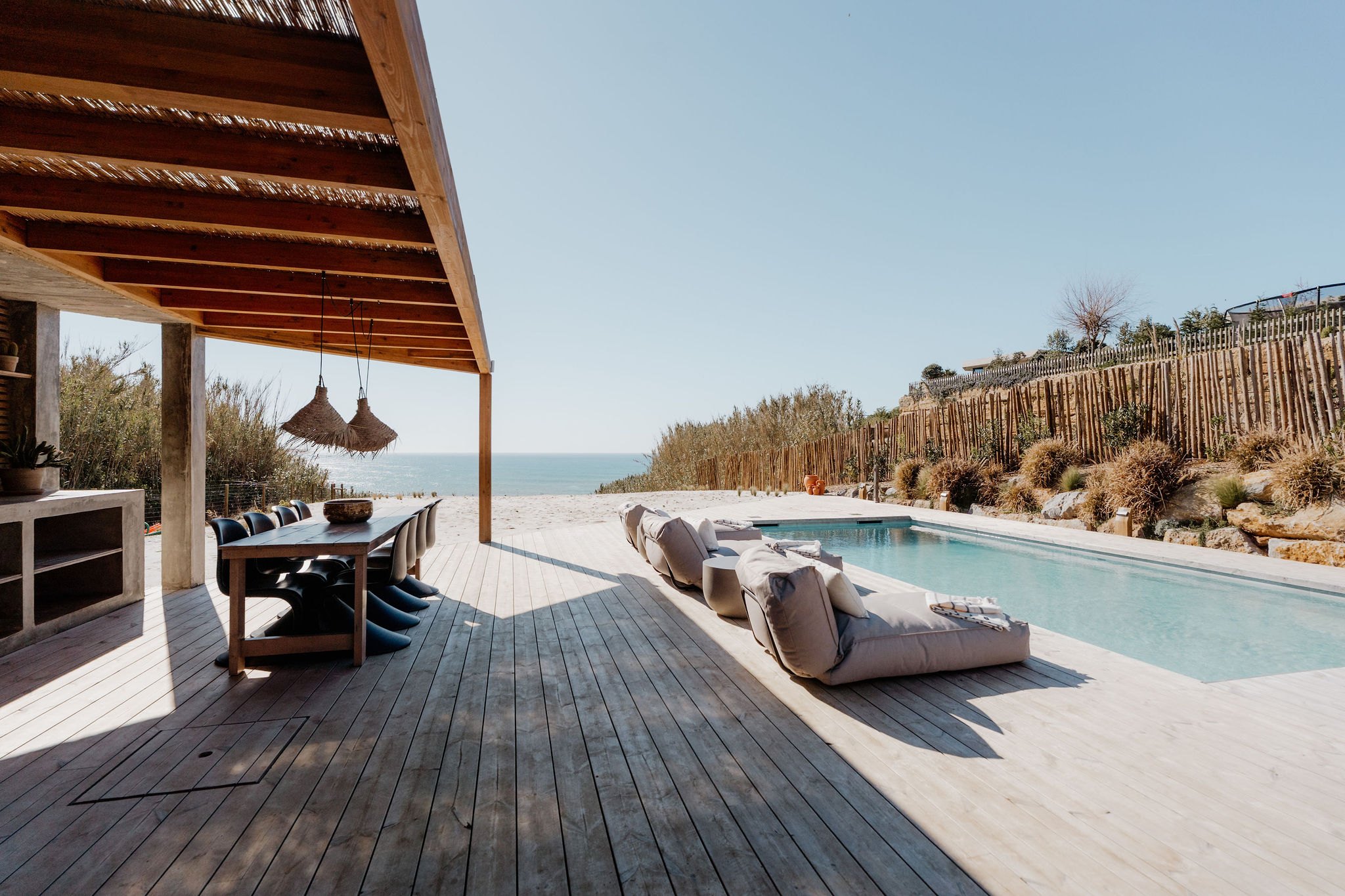 Loungers and a shaded pergola beside the pool, looking out to sea