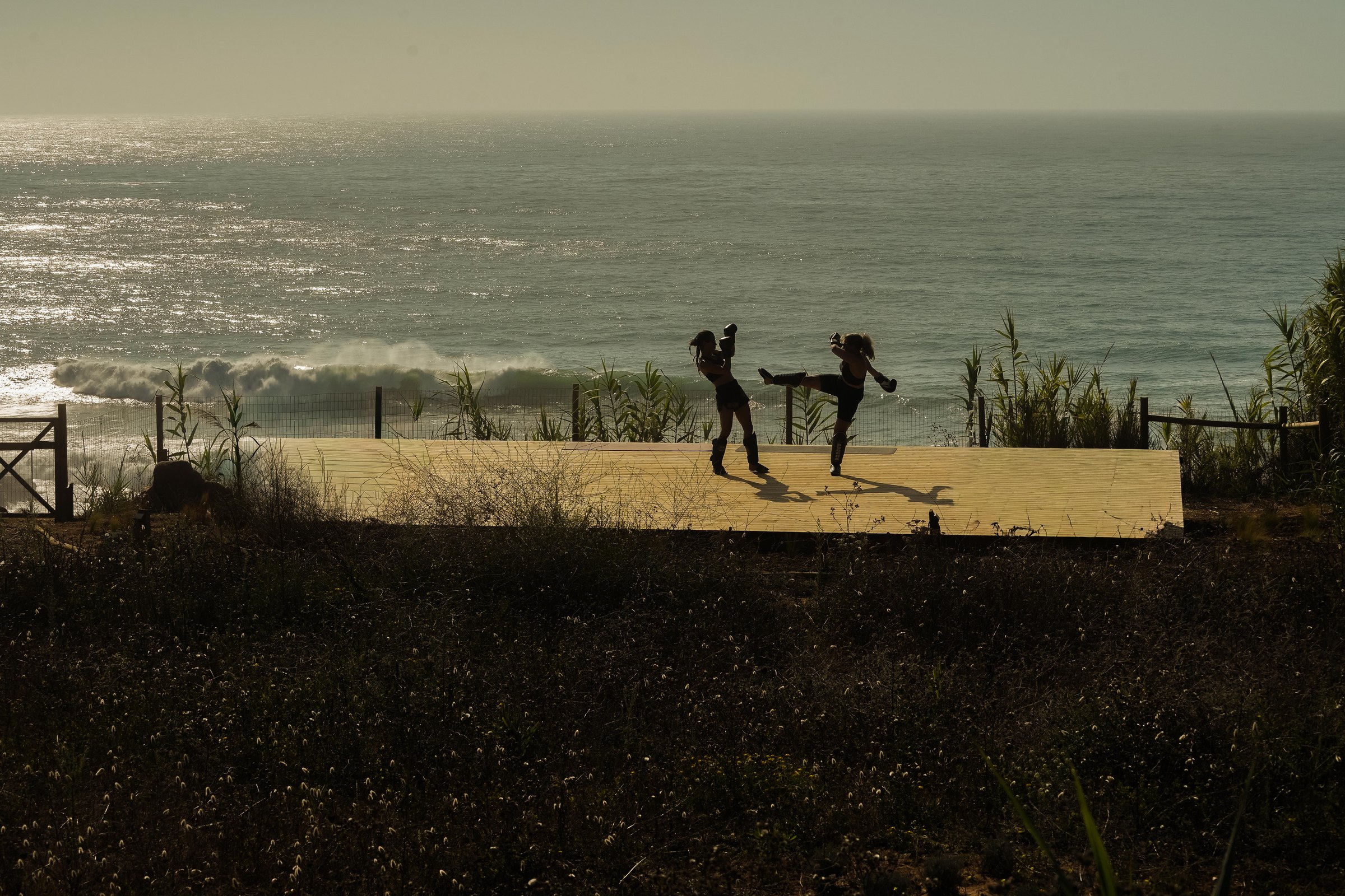 Two figures on the clifftop deck above the Atlantic surf
