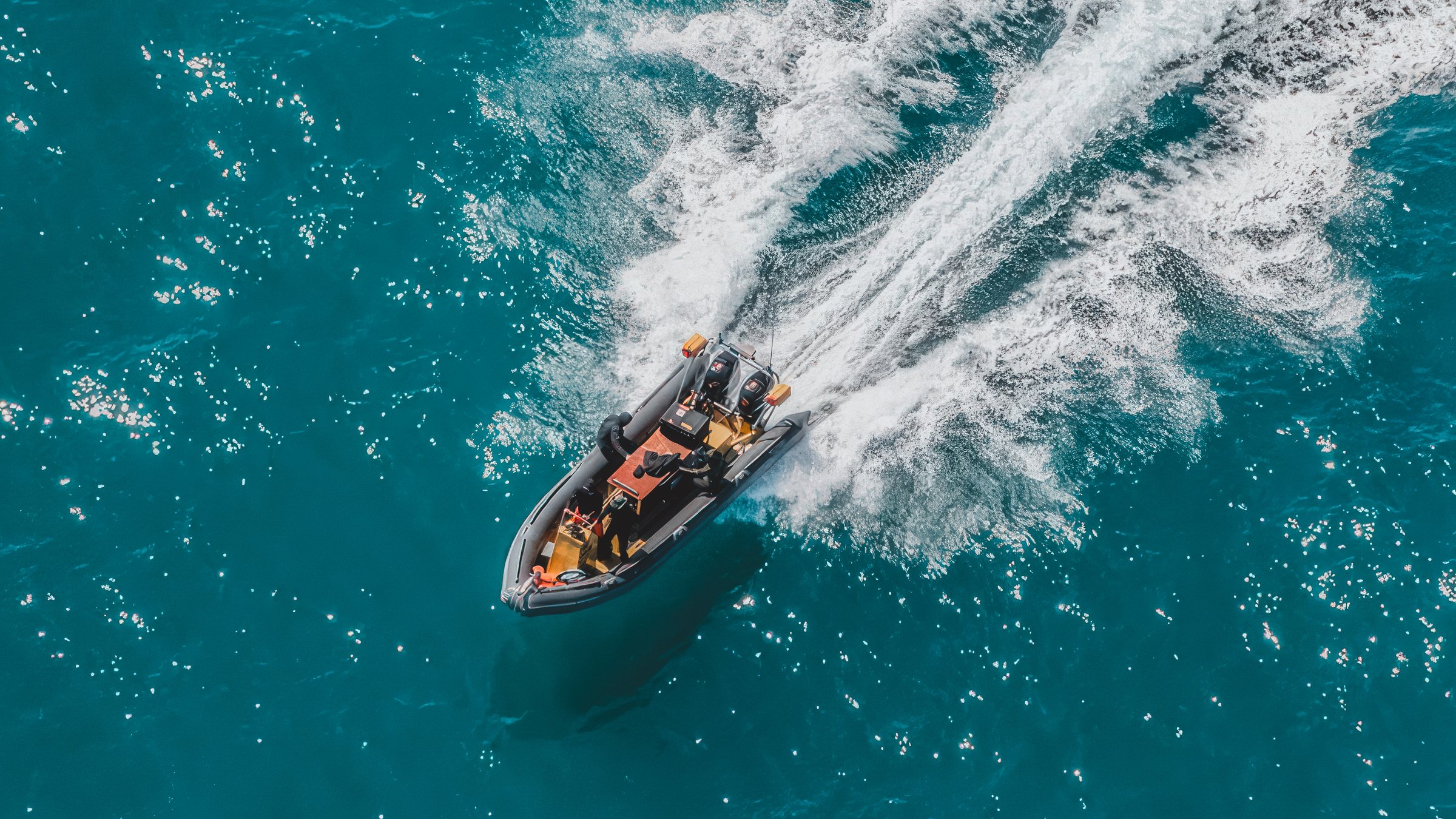 An aerial view of a dive boat speeding across turquoise Atlantic water off Faial