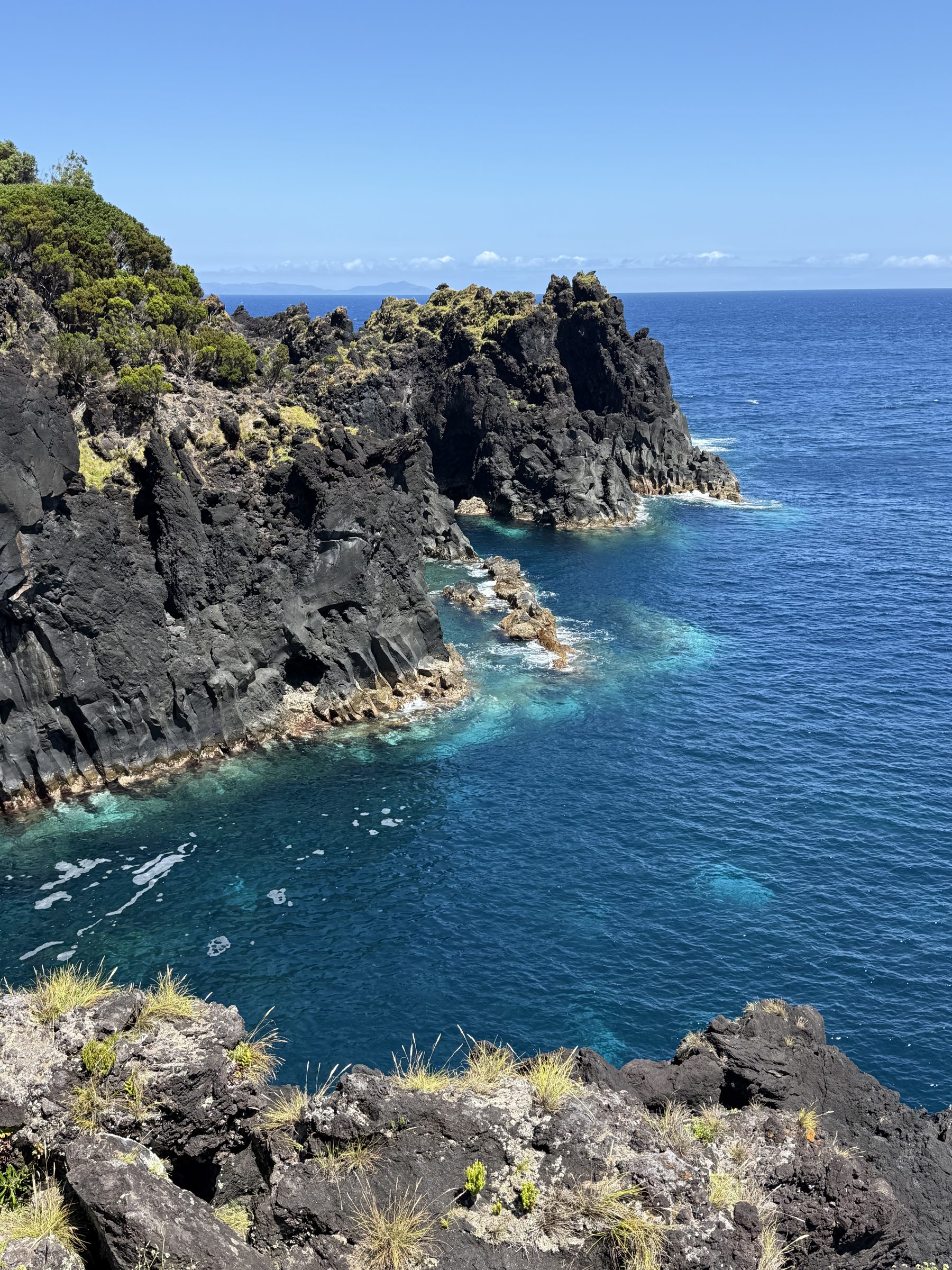 Black lava cliffs dropping into clear turquoise water