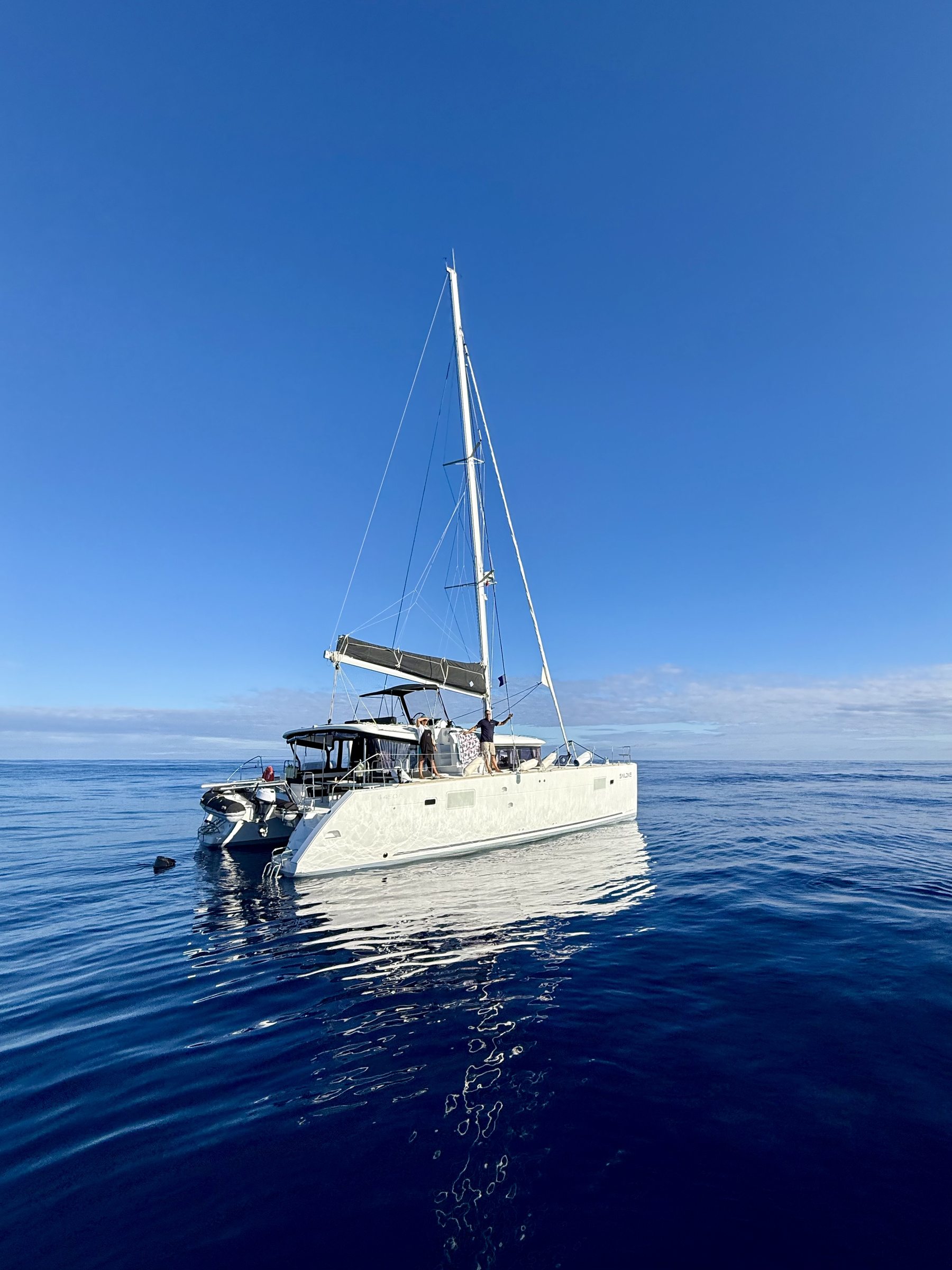 A catamaran at anchor on flat open ocean