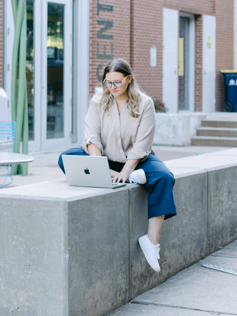 Elena sitting outside, using a macbook