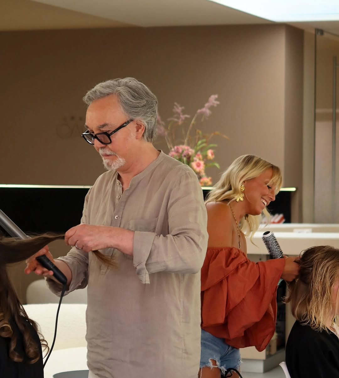 Two hairstylists curling and styling hair of clients in a modern salon.