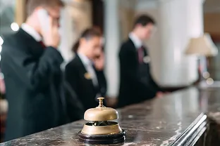 Comptoir d’hôtel avec cloche de réception et personnel en arrière-plan