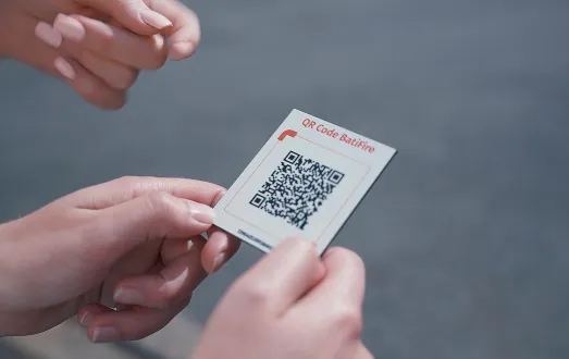 Une femme tient dans ses mains le QR Code du module Secourzs de BatiFire