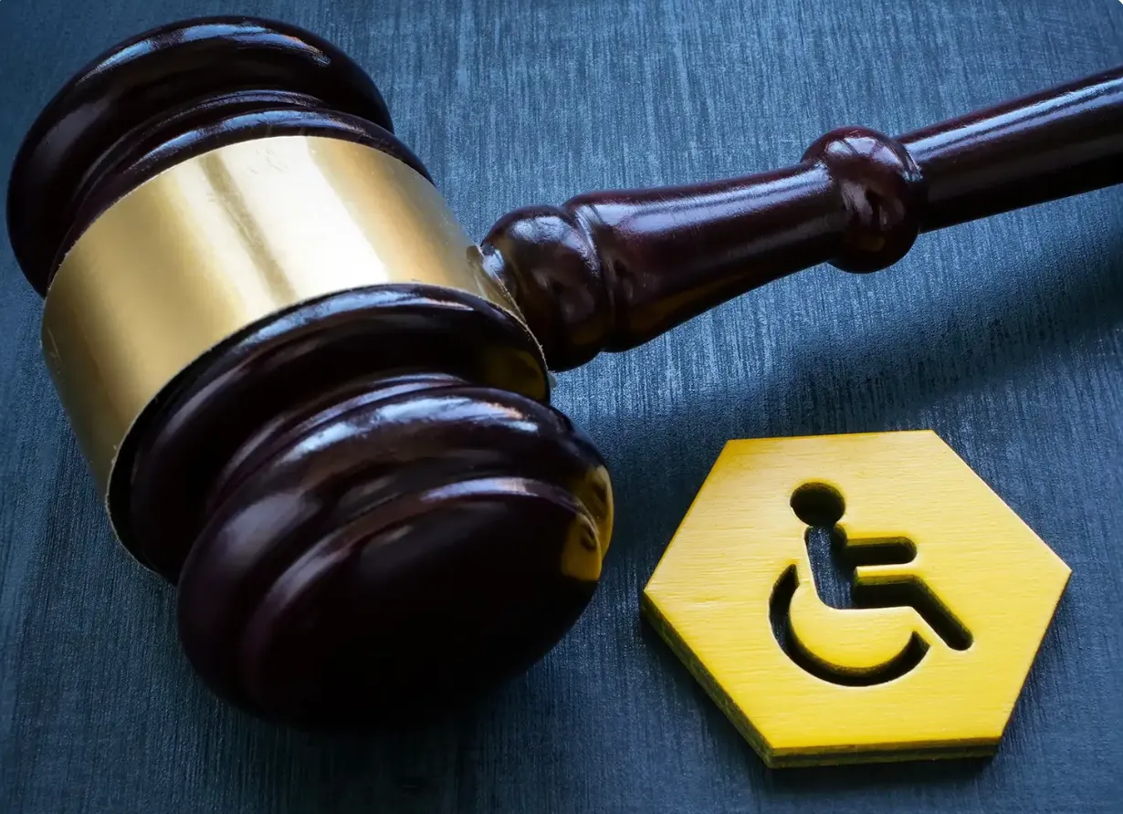 Marteau de juge à côté d’un pictogramme d’accessibilité, symbolisant la réglementation et les obligations légales liées à l’accessibilité des ERP.