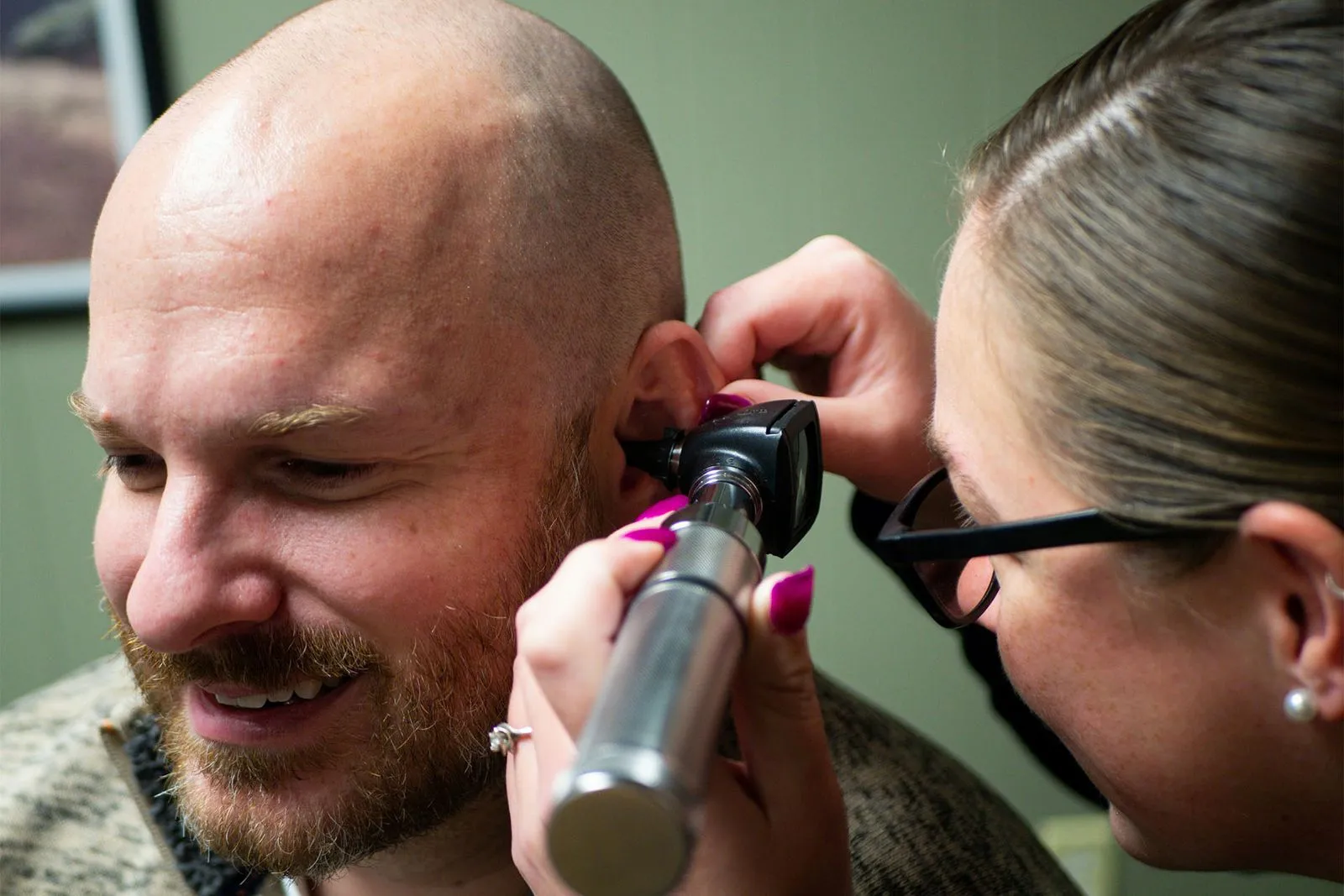 Doctor checking a man's ear canal.