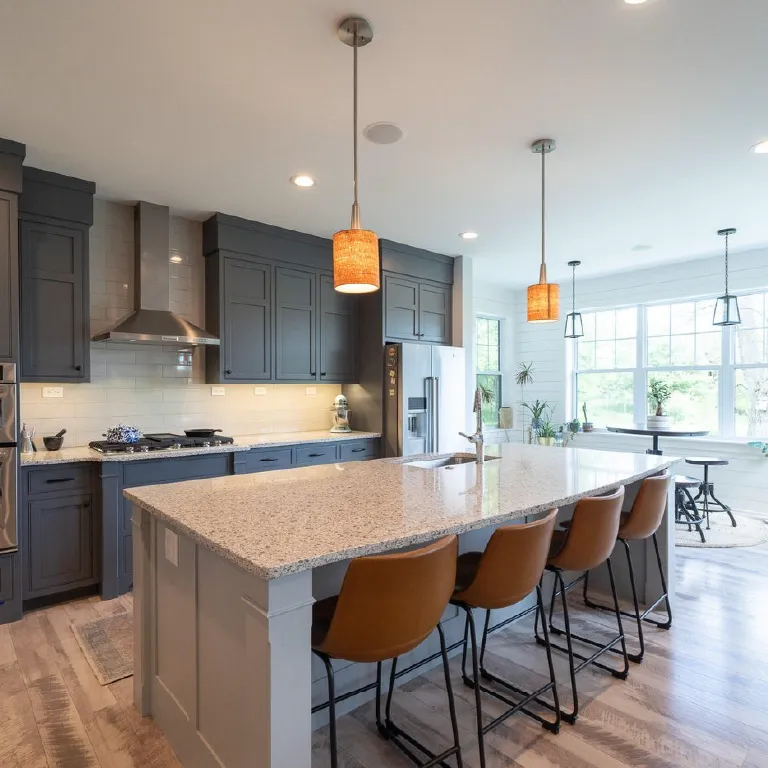 Modern kitchen with a large granite island, brown leather bar stools, and gray cabinets under warm pendant lights.