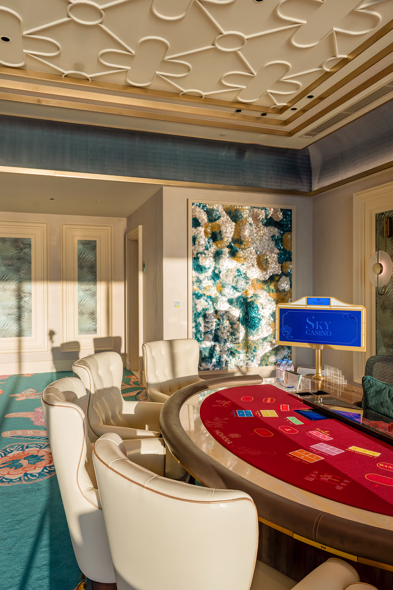 Private gaming room at Sky Casino, Hoiana Resort & Golf, featuring a Baccarat table, plush seating and contemporary artwork.
