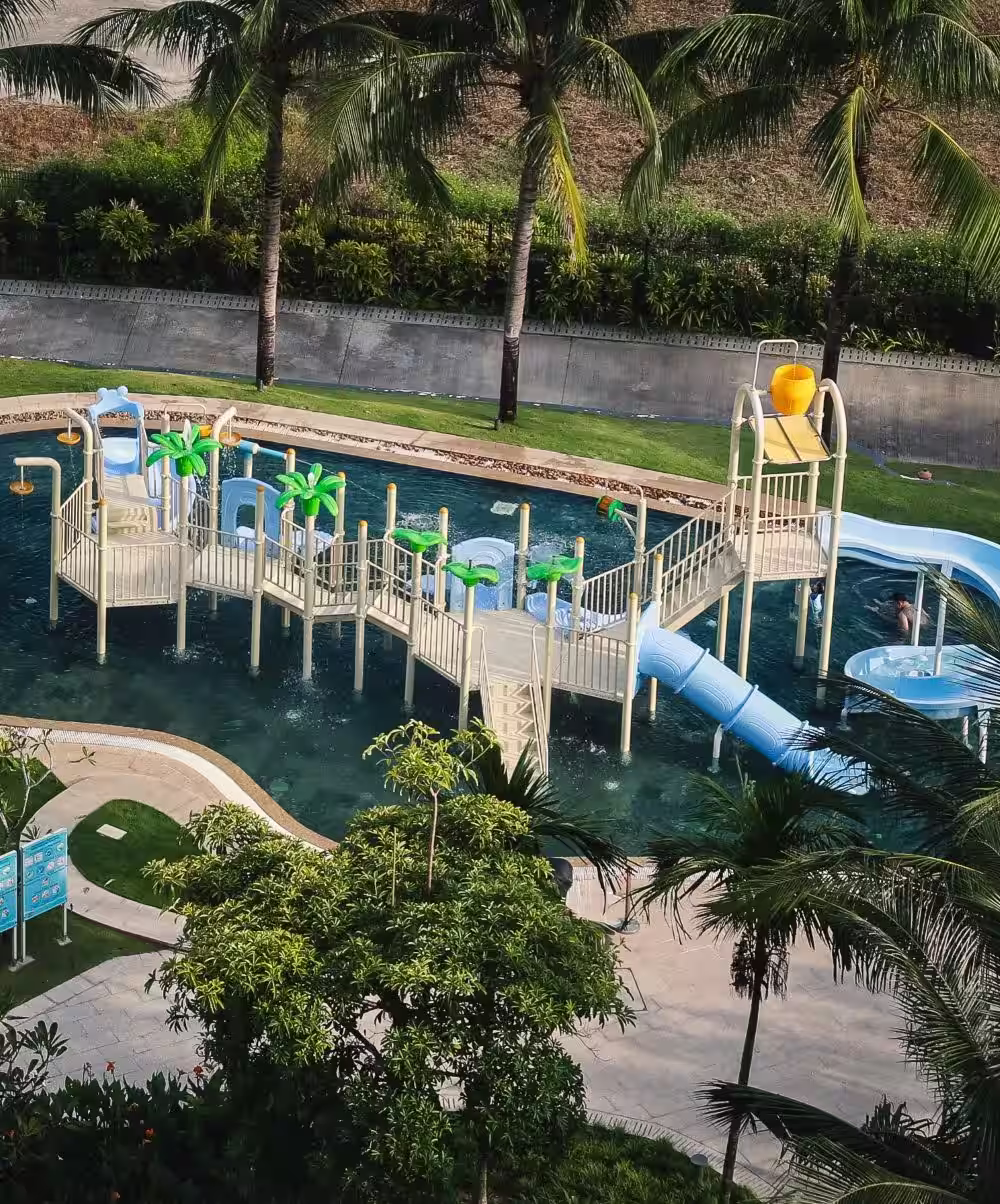 Mini water park at the Hoiana Residences pool, featuring colourful slides and splash-play structures surrounded by palm trees.