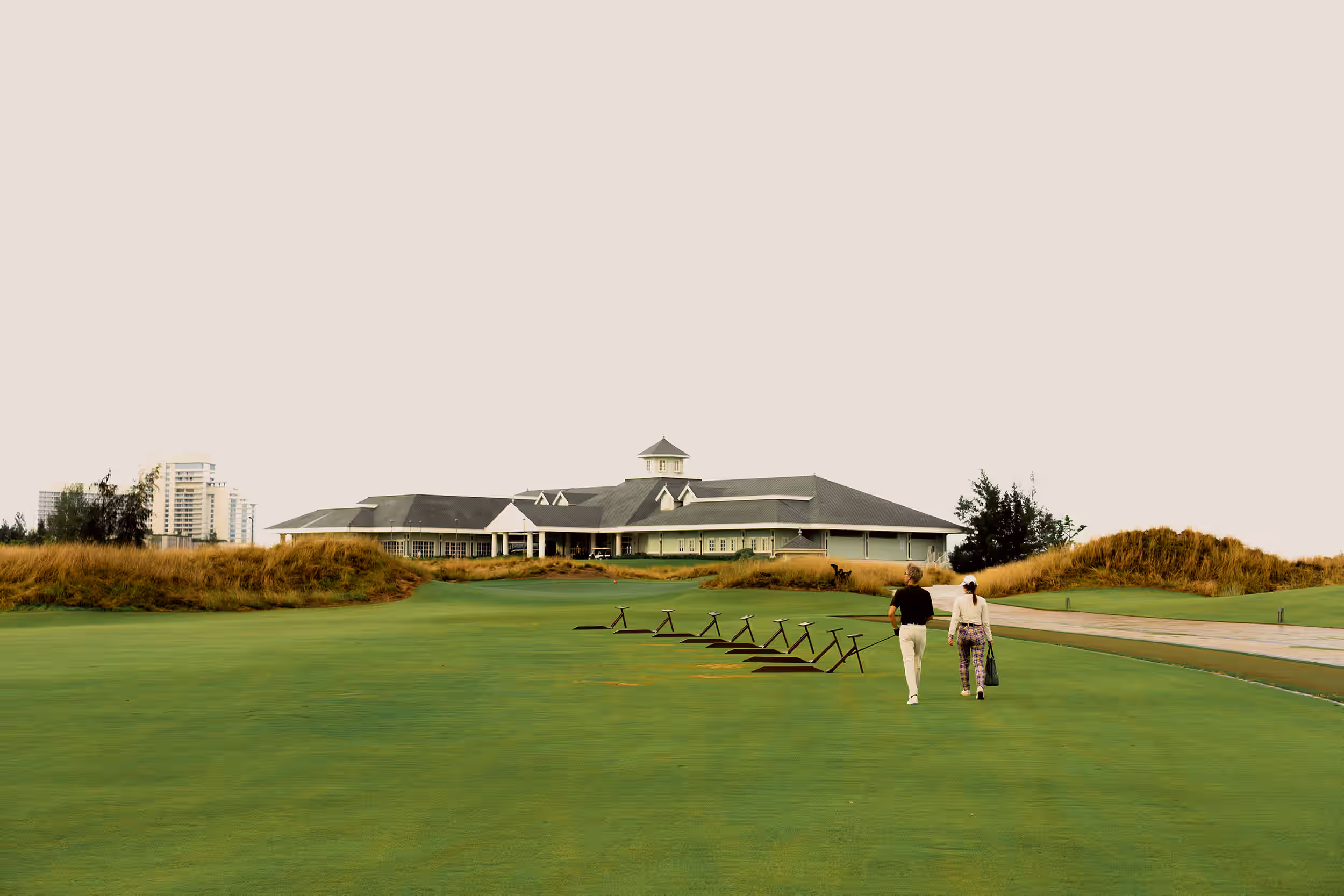 golfers walking across the practice area toward the Hoiana Shores Golf Club clubhouse.