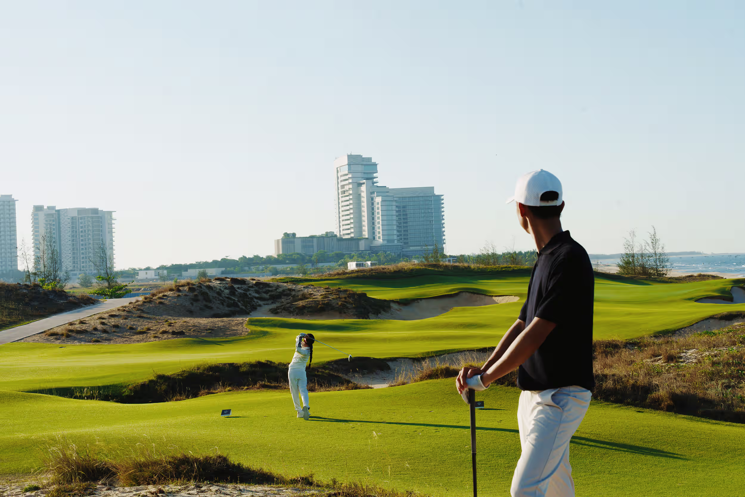 Golfers enjoying a round at Hoiana Shores Golf Club, with rolling fairways and Hoiana’s resort towers in the distance.
