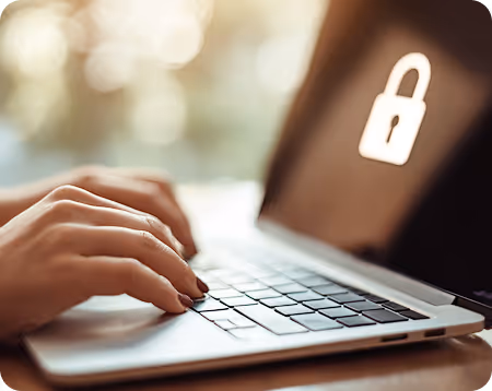 Hands typing on a laptop keyboard with a lock icon displayed on the screen indicating security.