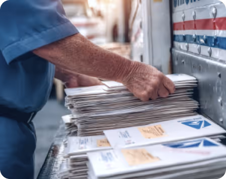 Postal worker placing a stack of mail into a mail sorting box.