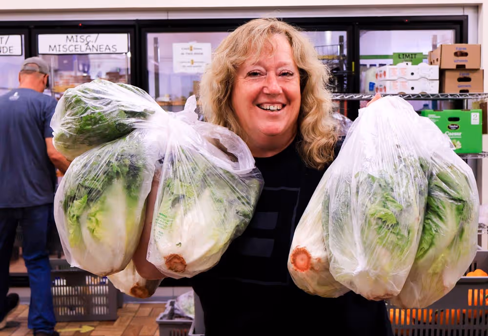 Fondy Food Pantry female volunteer holding large bags of fresh lettuce