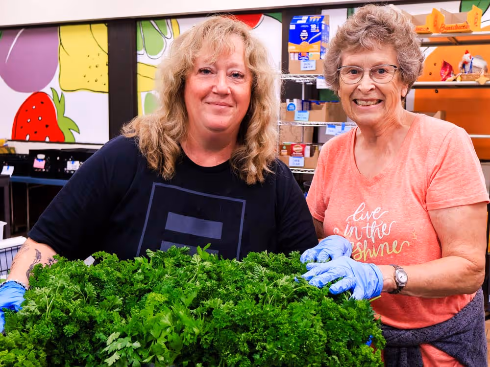 Fondy Food Pantry two female volunteers smiling while packaging fresh greens for the pantry