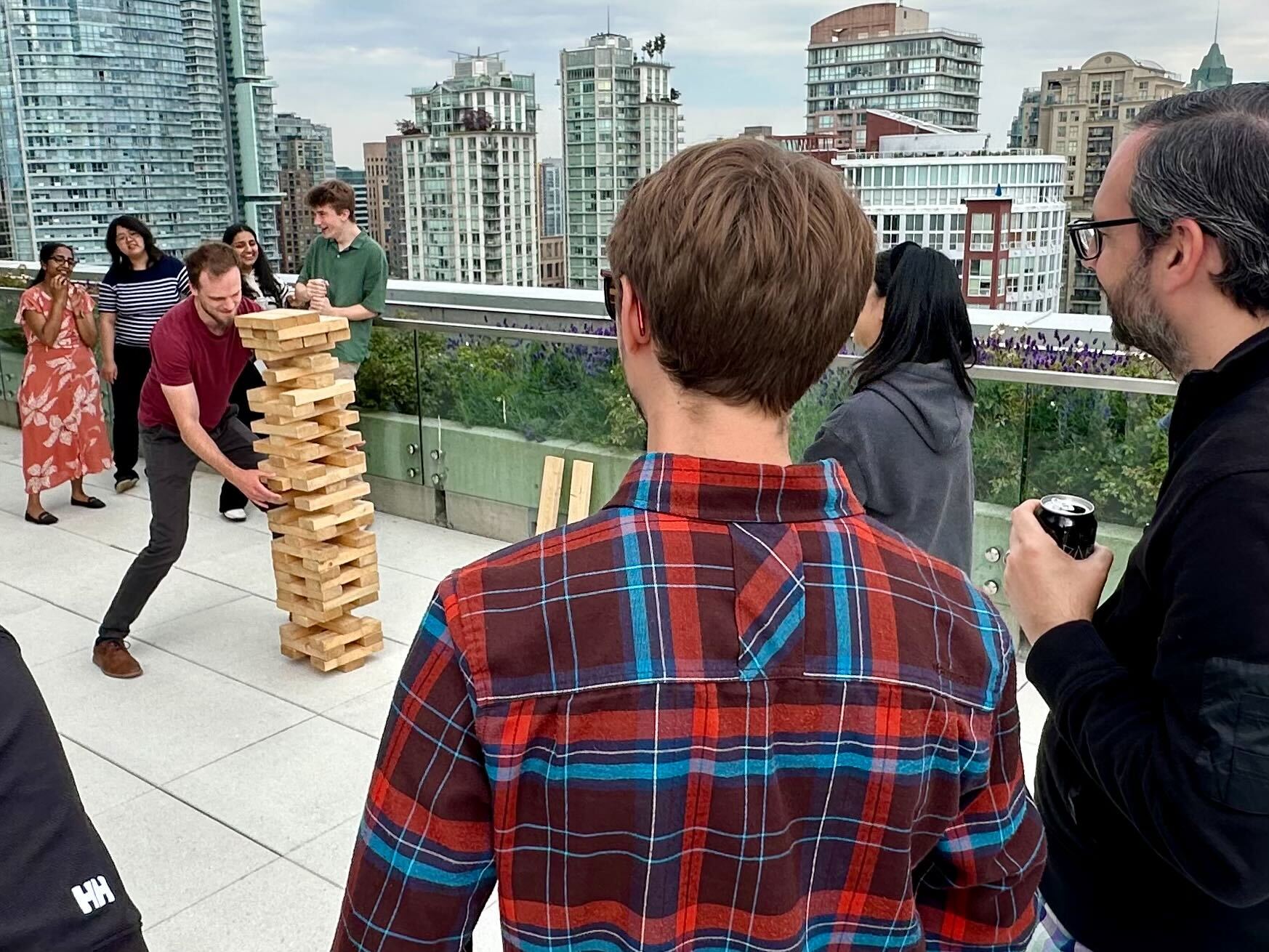 Group of people on a rooftop patio in Vancouver playing a giant Jenga game with skyscrapers in the background.