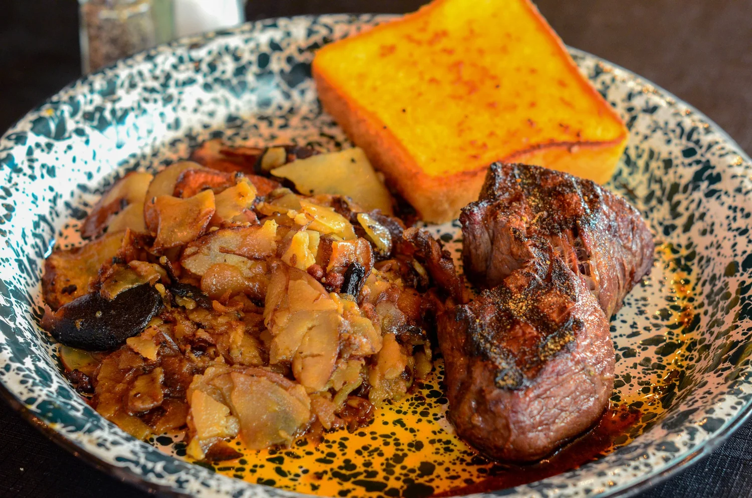 A plate of food with a piece of meat and a piece of bread.