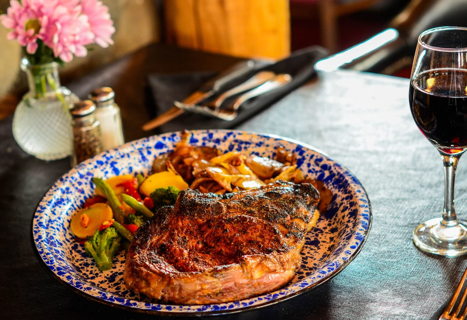 A plate of food with a steak and vegetables on a table.