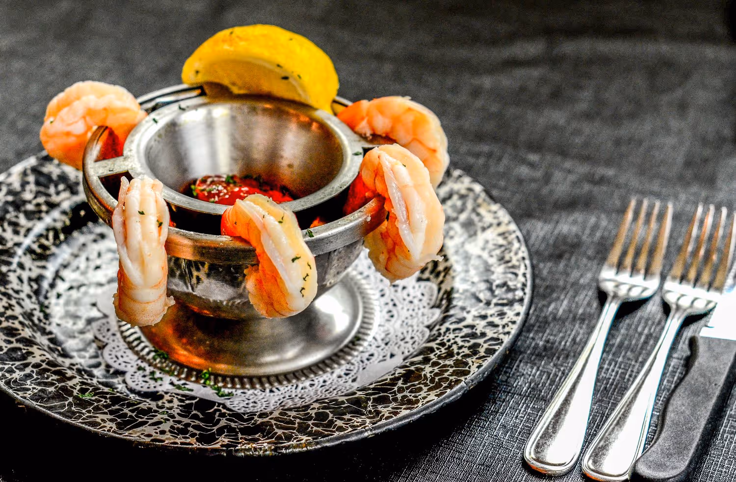 A silver bowl with shrimp and lemon wedges.