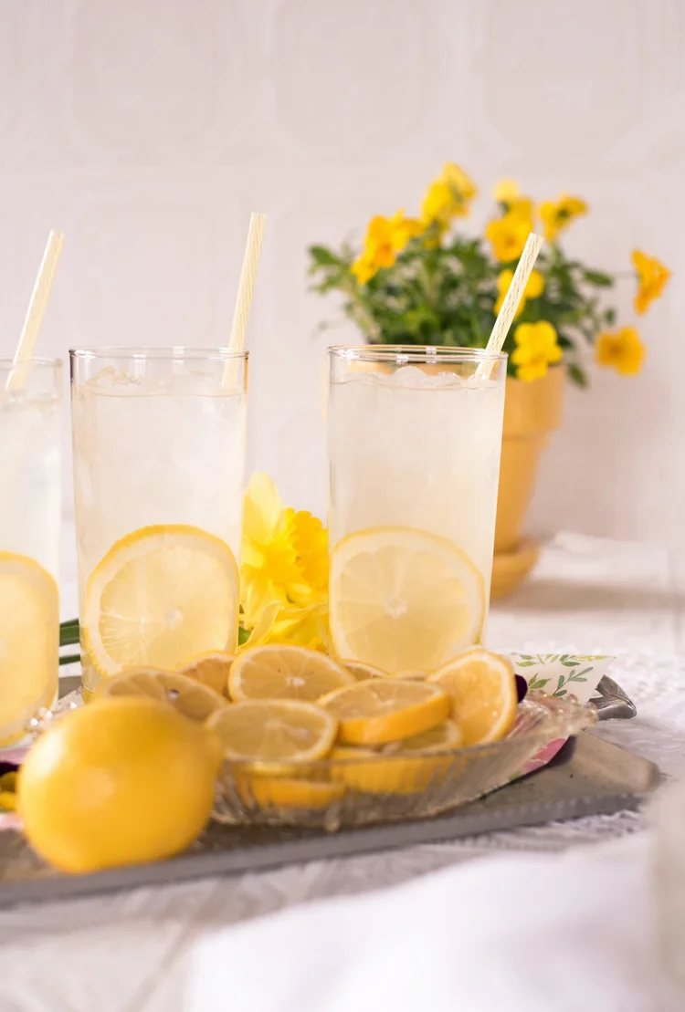 Two glasses of lemonade with lemon slices in them.