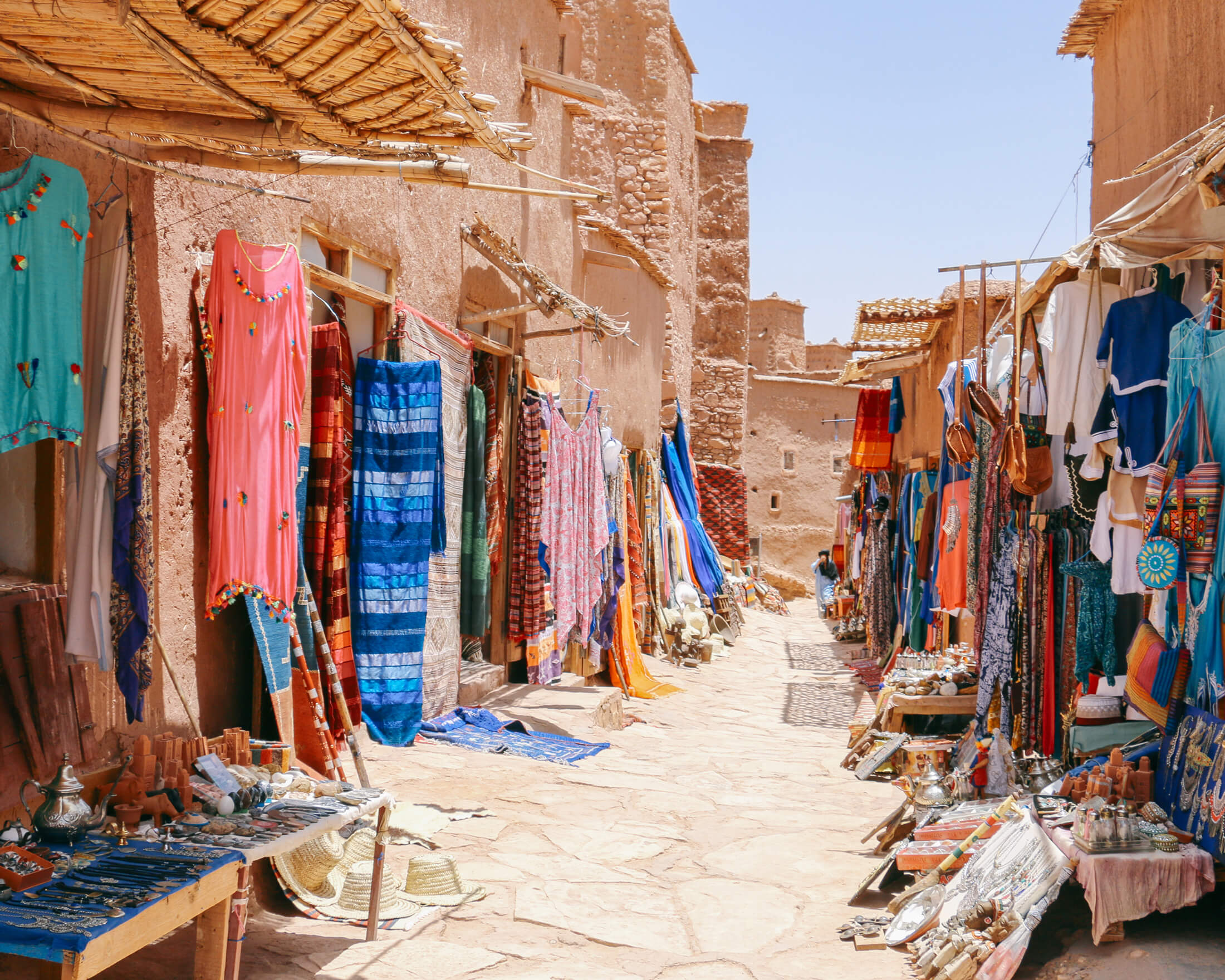 Narrow souk alley with colorful textiles and crafts displayed in Morocco.