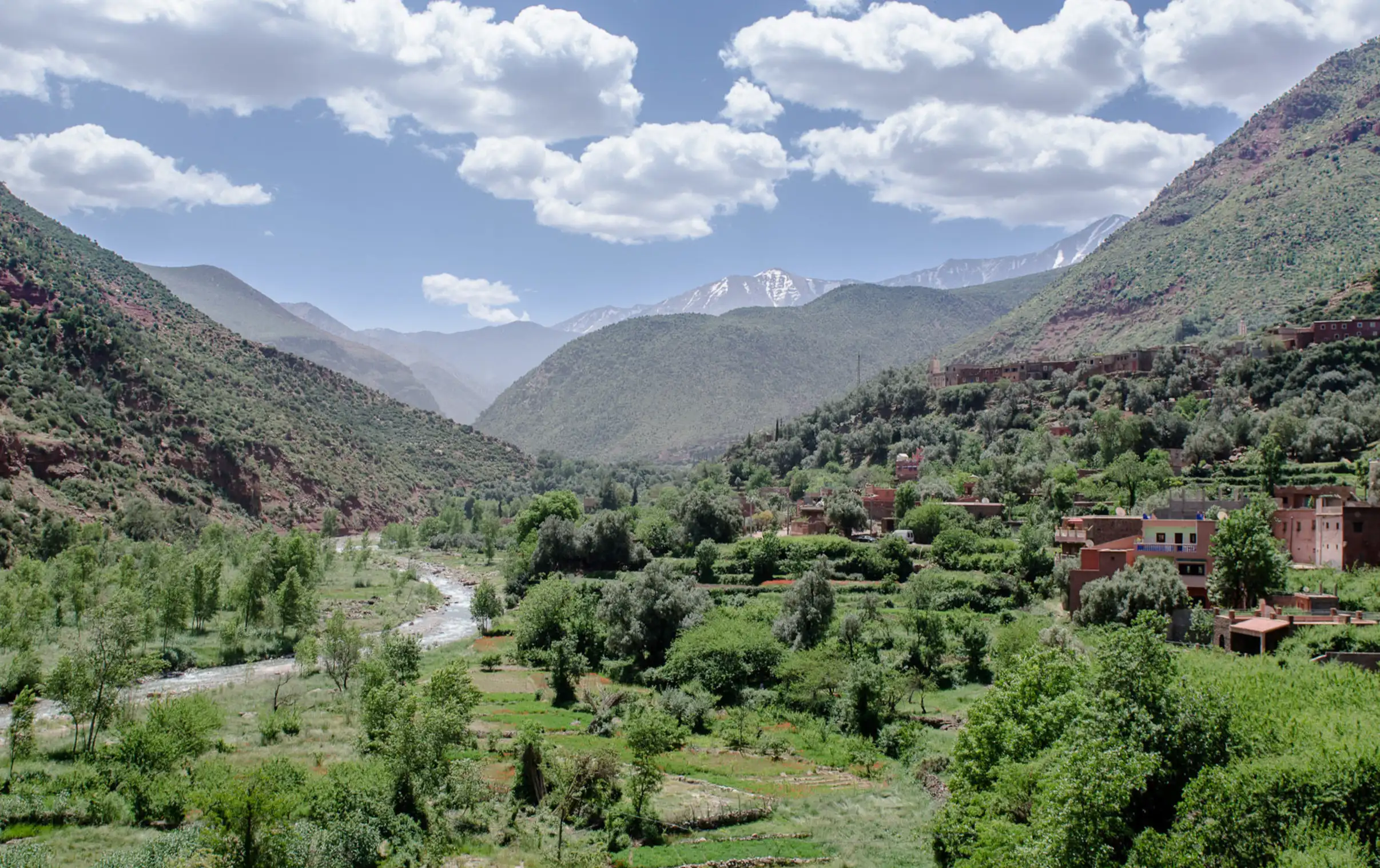 Moroccan Ourika valley with lush green landscape and distant snow-capped peak of Toubkal during a day tour with Moroccan Guides Travel.
