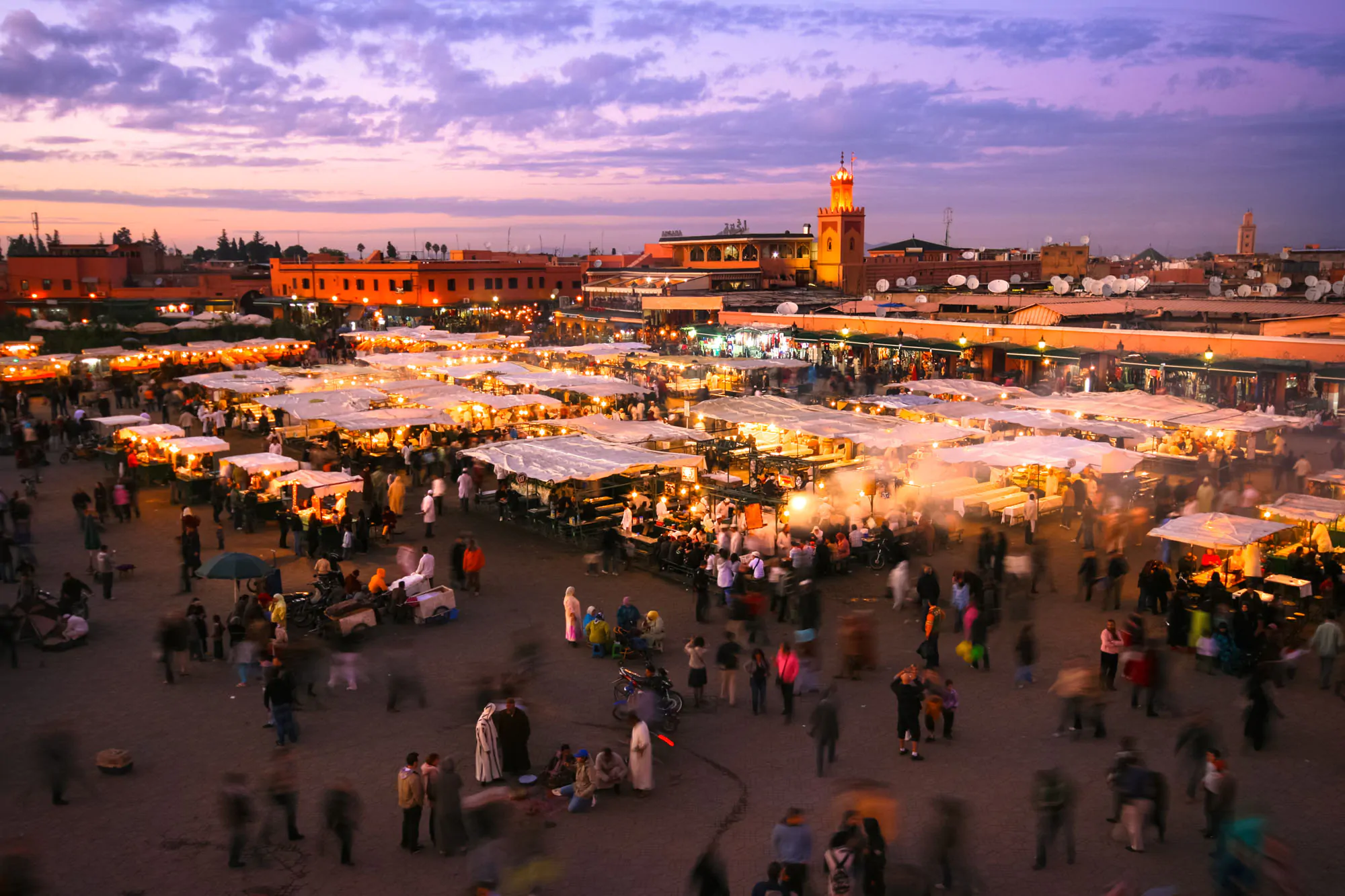 Jammaa Elfna at dusk with vibrant lights and traditional local food in Marrakech, Morocco.