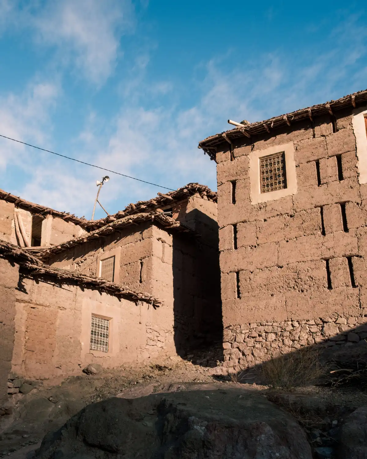 Traditional adobe buildings with stone base under bright blue sky in the Ait Bougemez valley in the high atlas mountains
