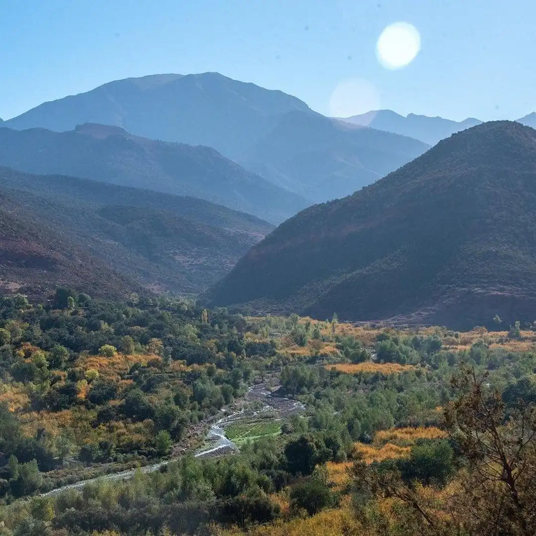 Mountain Ourika valley  in the Atlas Moutains of Morocco famous for trekking and excursions with winding river, trees, and layered peaks under bright sun
