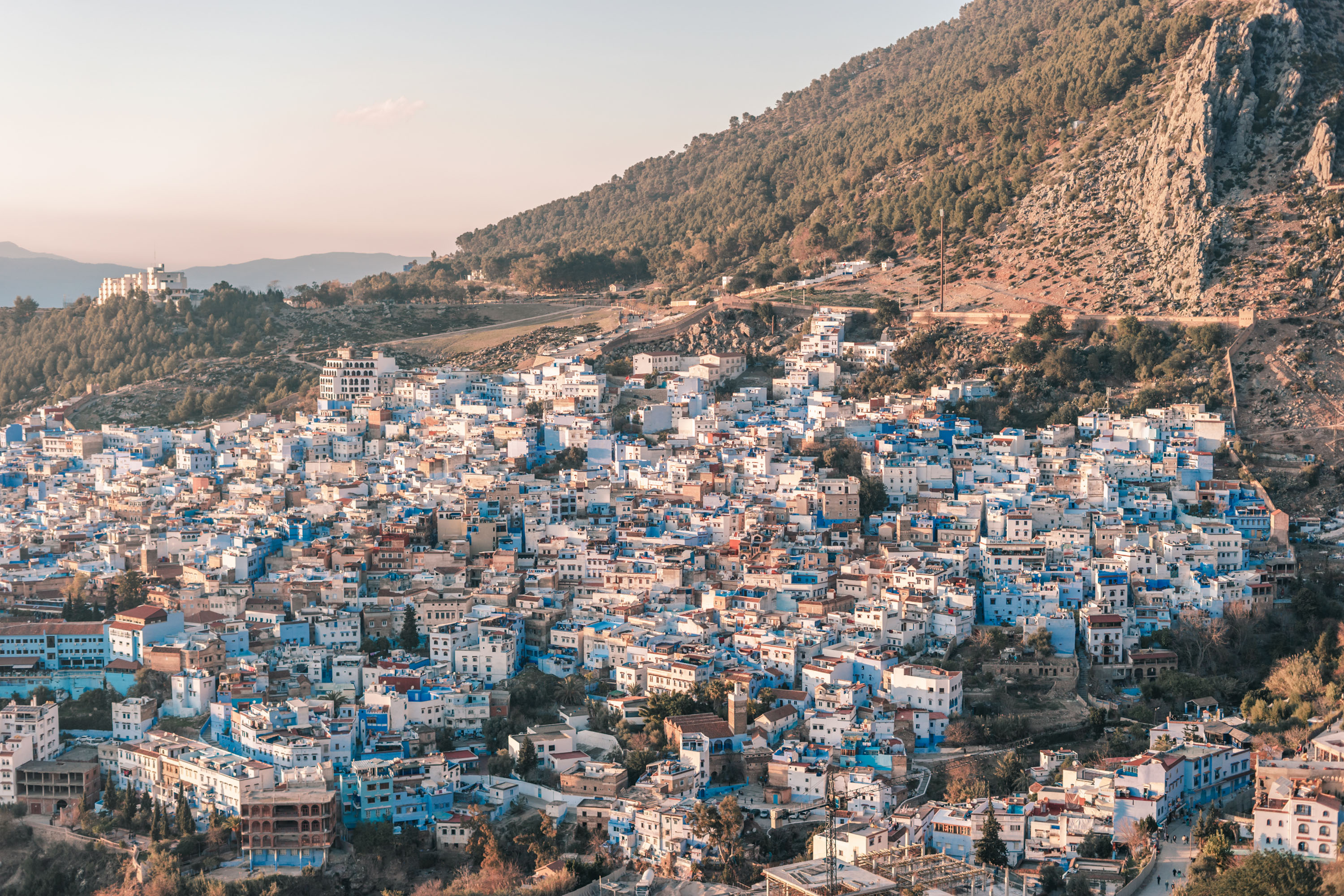 Blue and white buildings of Chefchaouen nestled in Moroccan mountain landscape in the north of Morocco