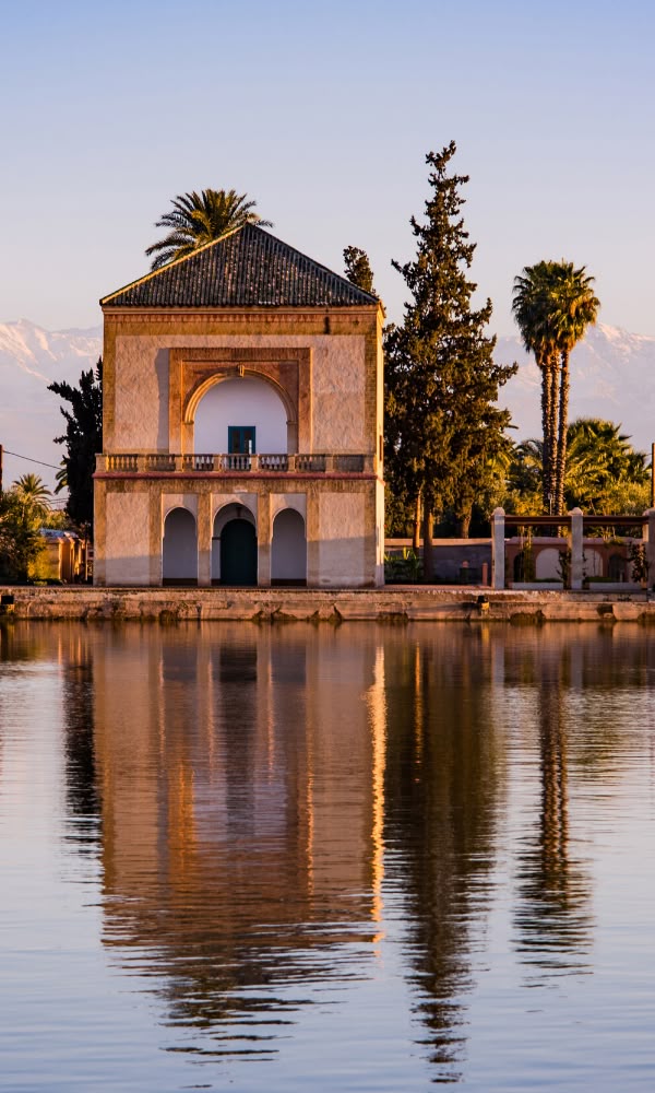 Moroccan pavilion Famous Menara In Morocco's Red Citiy Marrakech with arched windows reflected in calm water at sunset during a day tour With Moroccan Guides Travel.