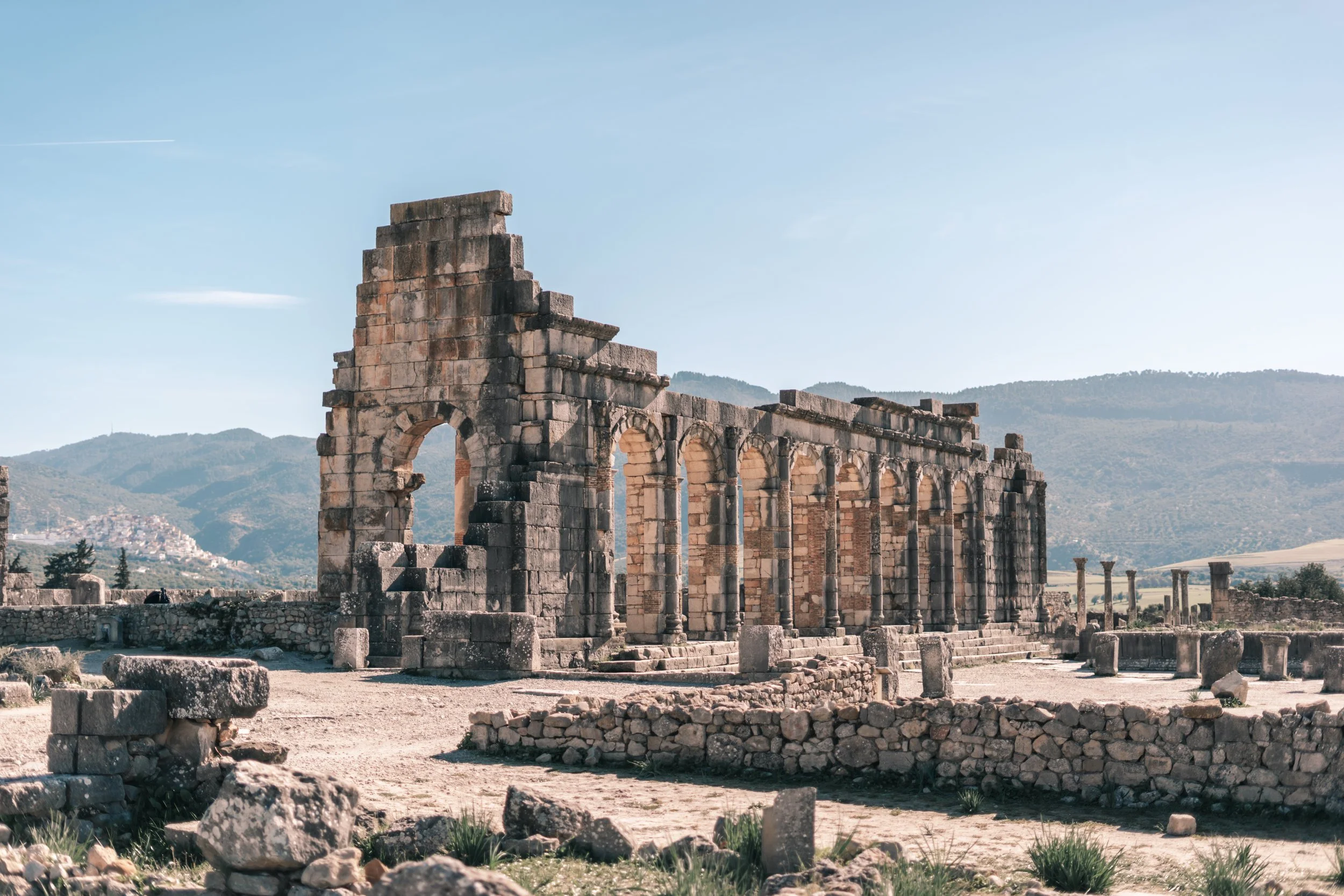 Ancient Volubilis Roman ruins with stone arches and columns in mountainous landscape