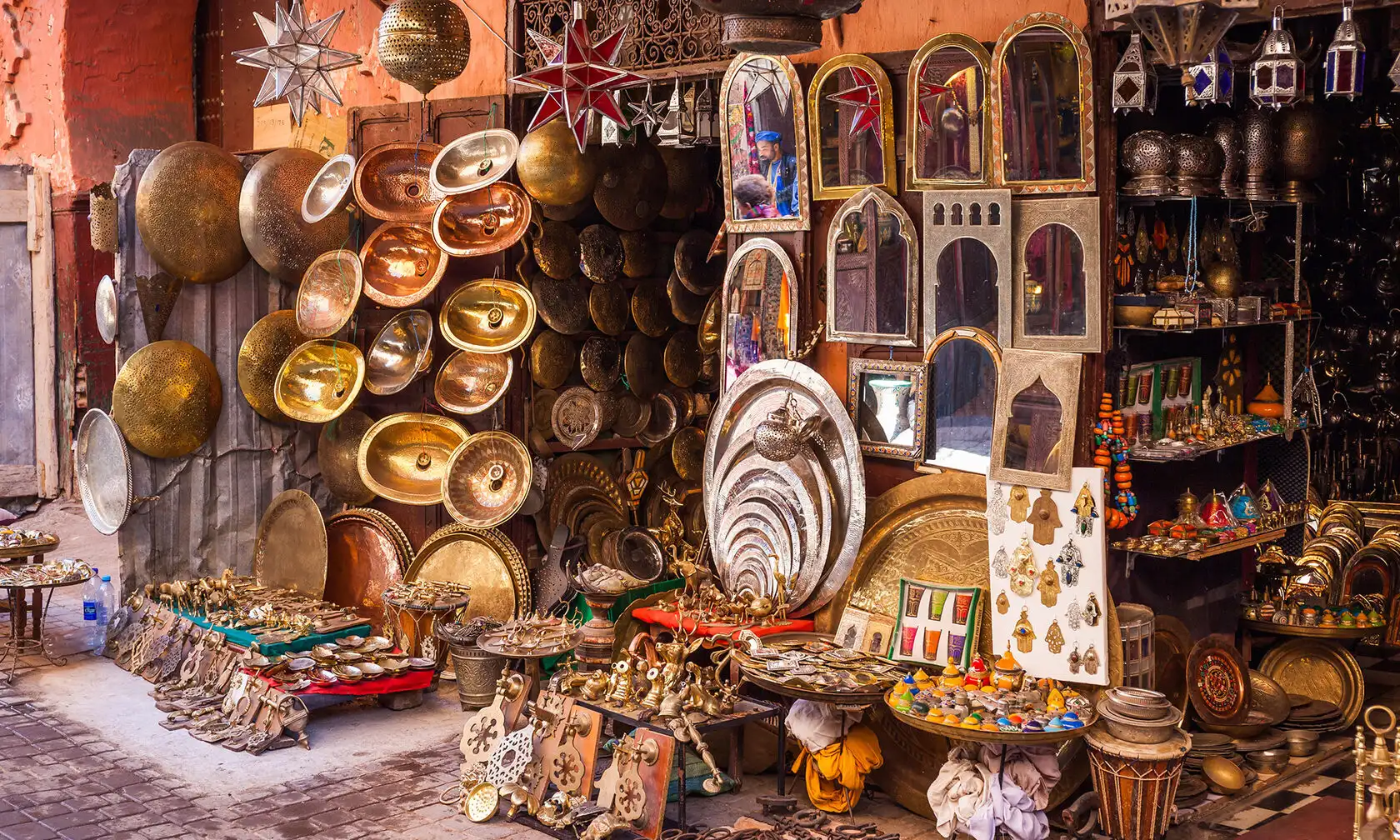 Colorful Moroccan Marrakech market stall with metallic plates, lanterns, and ornate decor in the old Medina during a tour with Moroccan Guides Travel