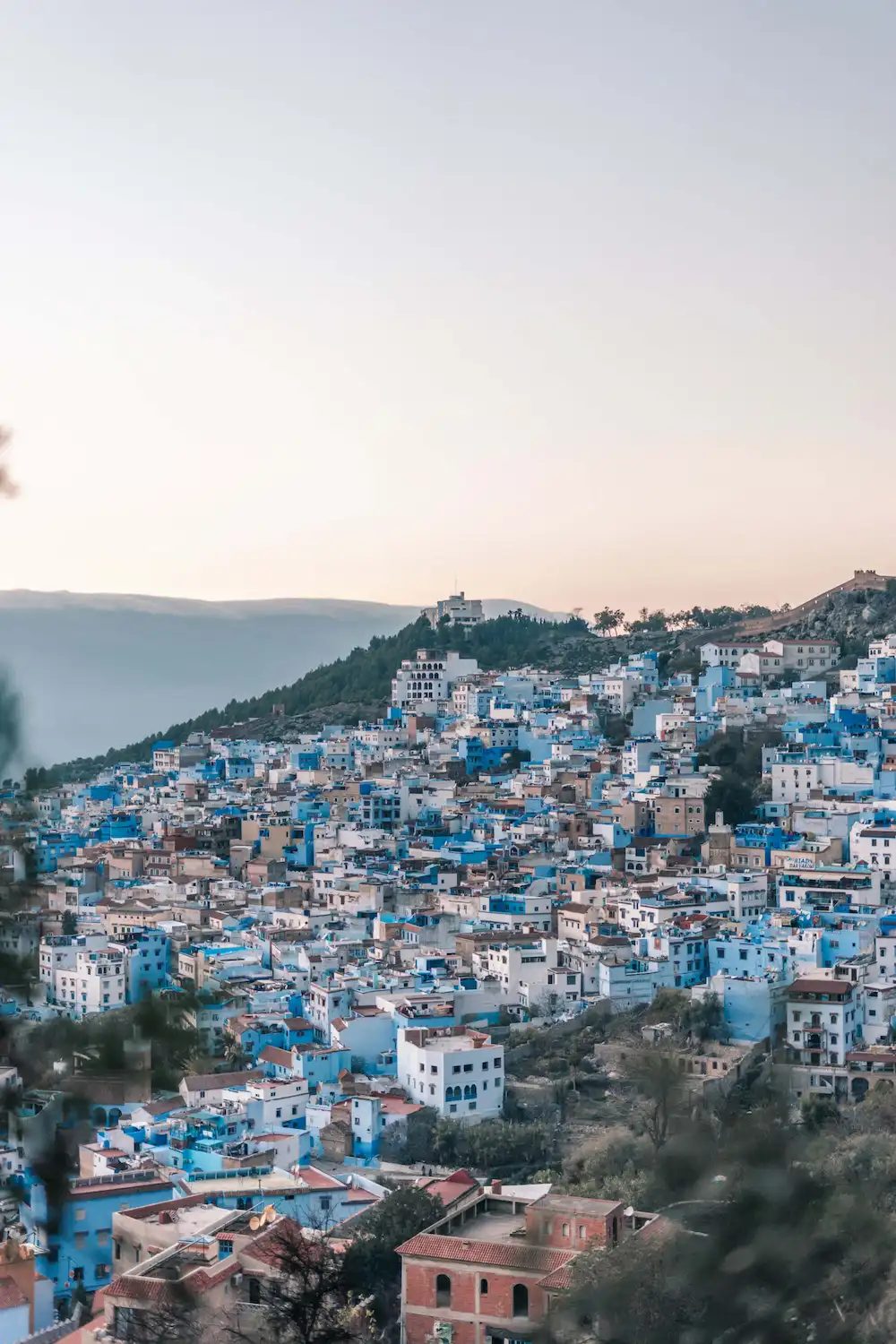 Chefchaouen, Moroccan blue city nestled in mountainous landscape at sunset during a tour with Moroccan Guides Travel