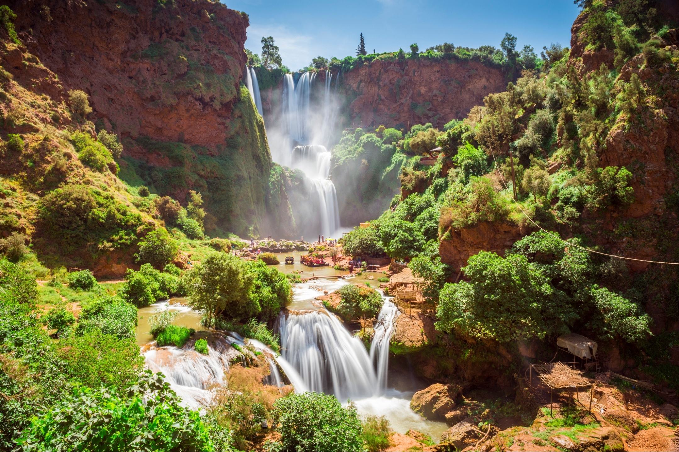 Cascading Ouzoud waterfalls surrounded by lush green cliffs and rocky landscape during a tour with Moroccan Guides Travel