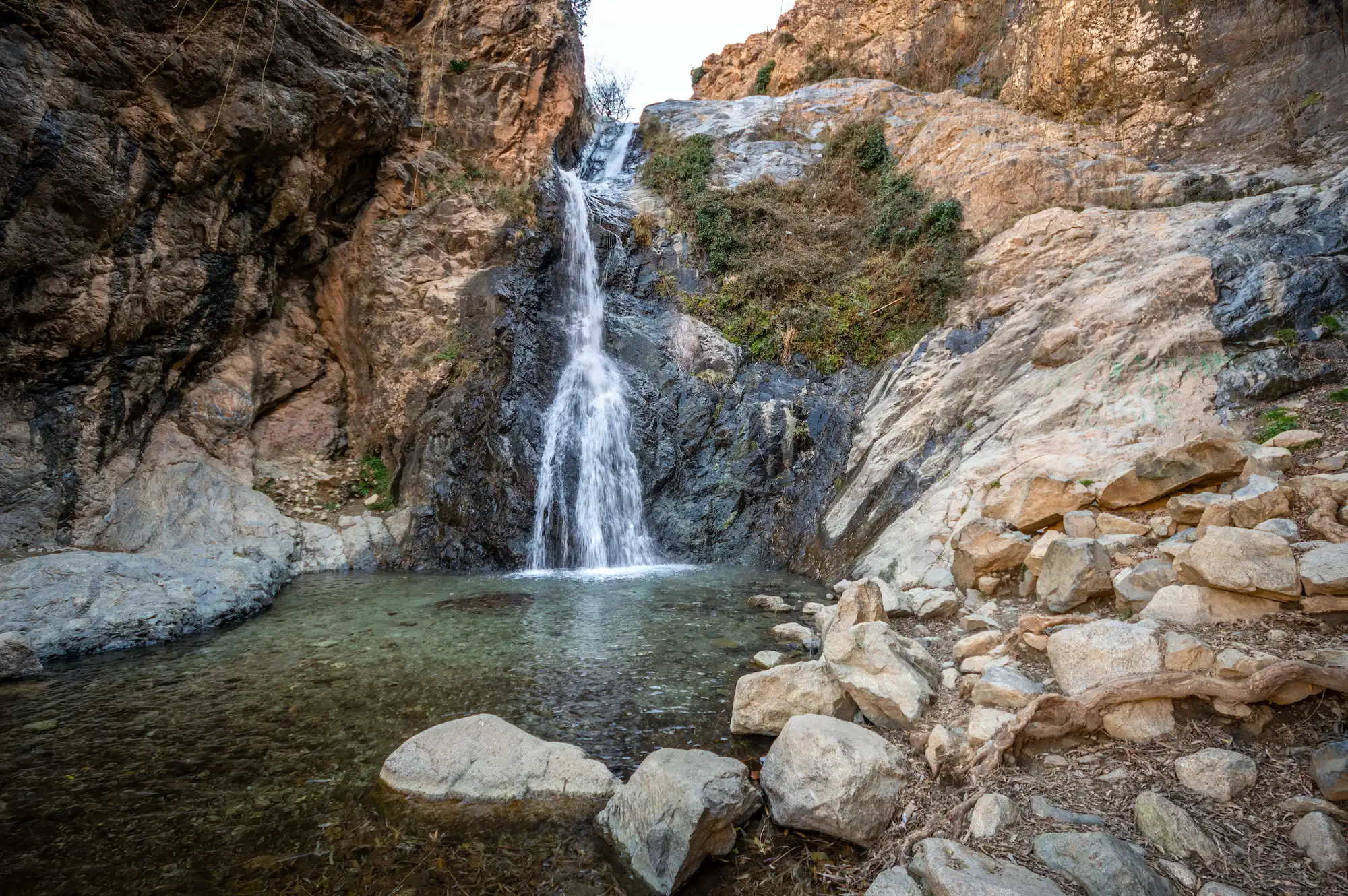 Serene Ourika waterfall cascading into clear pool surrounded by rocky mountain terrain during a tour with Moroccan Guides Travel
