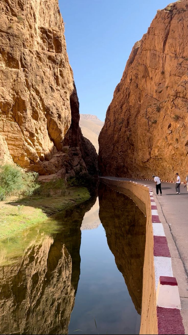 Rocky Toudgha Gorges canyon with calm water reflecting steep cliffs and walkway in Tinghir Morocco