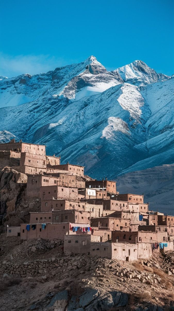 Moroccan village of Imlil nestled against snow-capped Atlas Mountains with blue sky