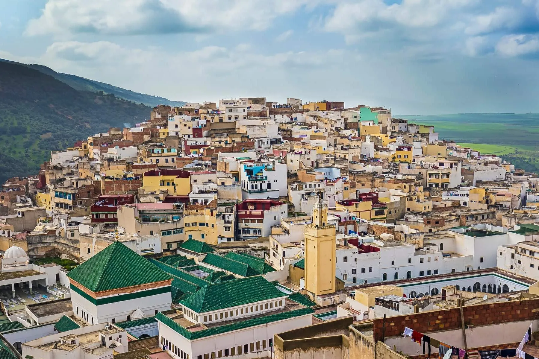 Crowded Moroccan city Of Meknes with colorful buildings nestled against mountainous landscape