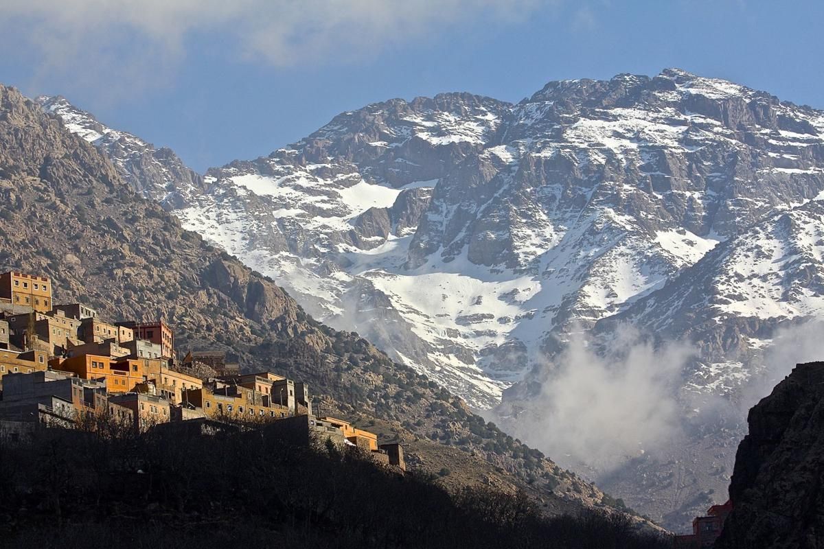 Snowy high atlas mountain peaks with small Imlil village nestled on rocky mountainside during a tour with Moroccan Guides Travel