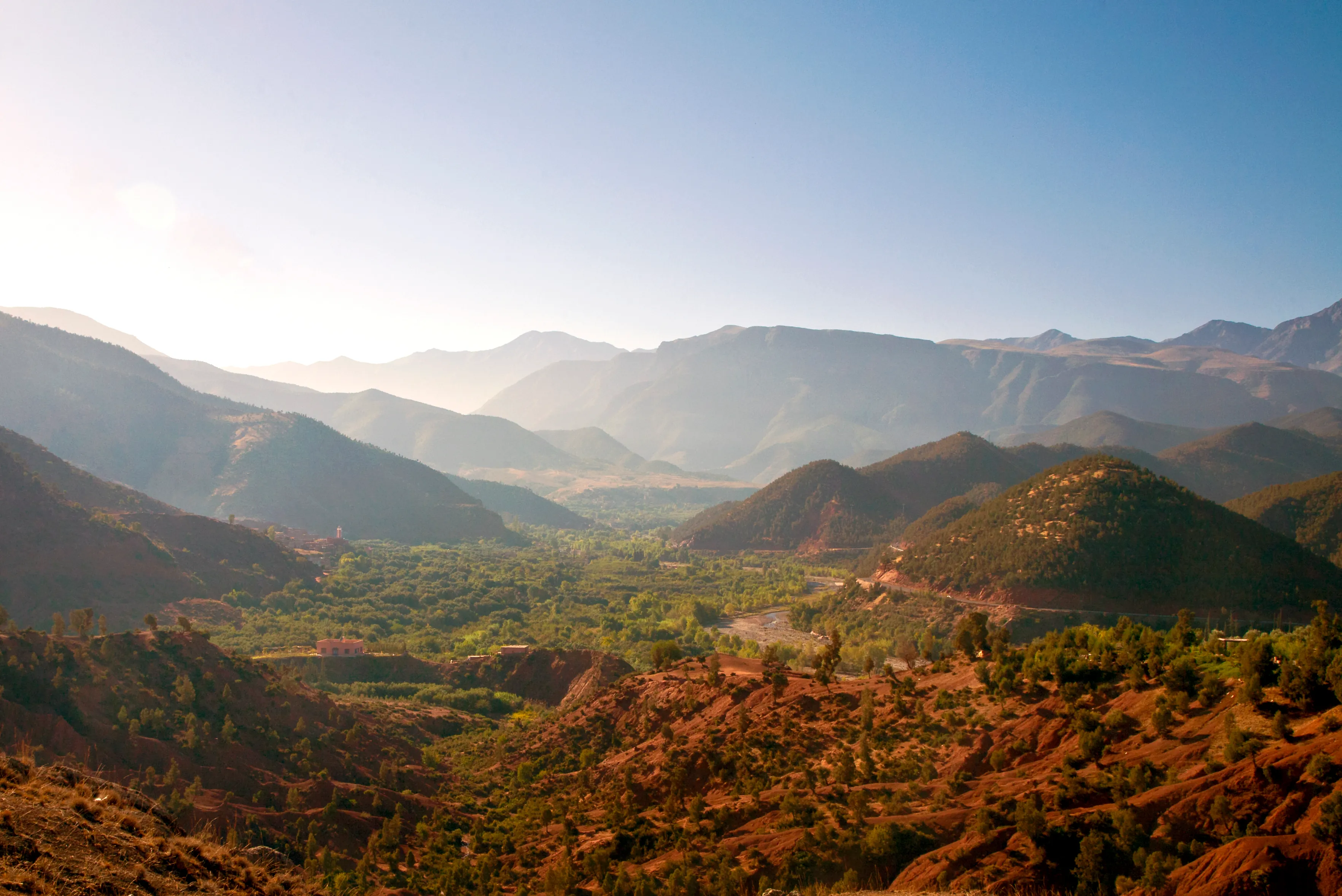 Scenic mountain Ourika valley with layered peaks, green forest, and rocky terrain during a tour with Moroccan Guides Travel