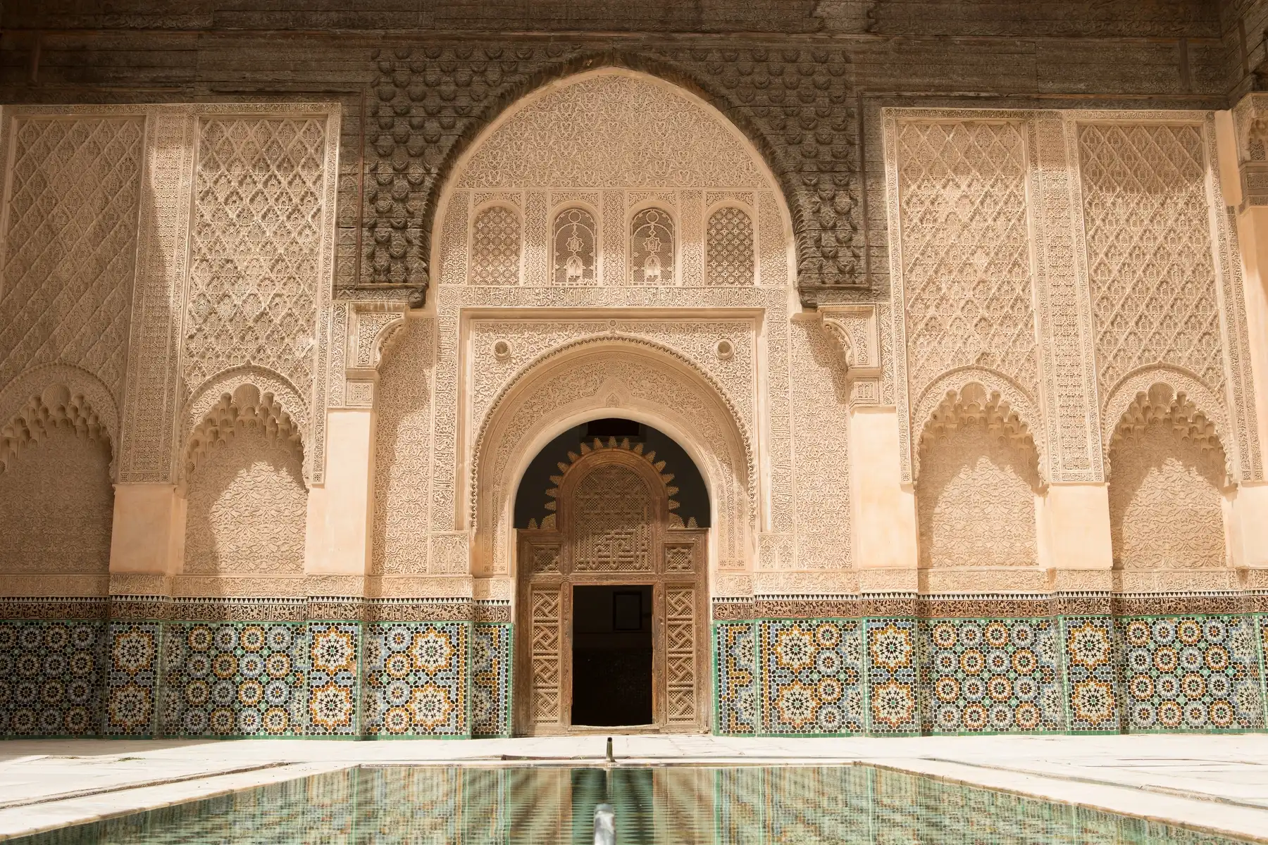 Ornate Moroccan Sidi Youssef Madrassa with intricate moroccan traditional tilework and reflective pool during a tour with Moroccan Guides Travel