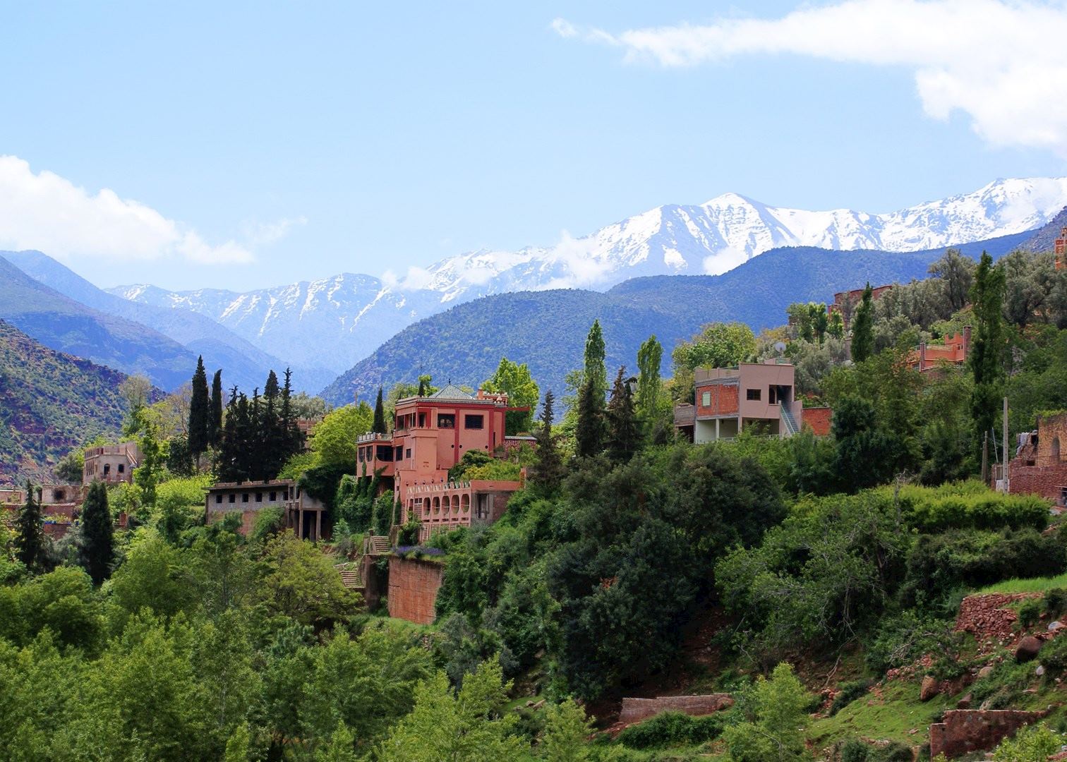 Mountainous landscape with red buildings nestled among lush green trees in the Ourika Valley of Morocco during a guided tour Moroccan Guides travel