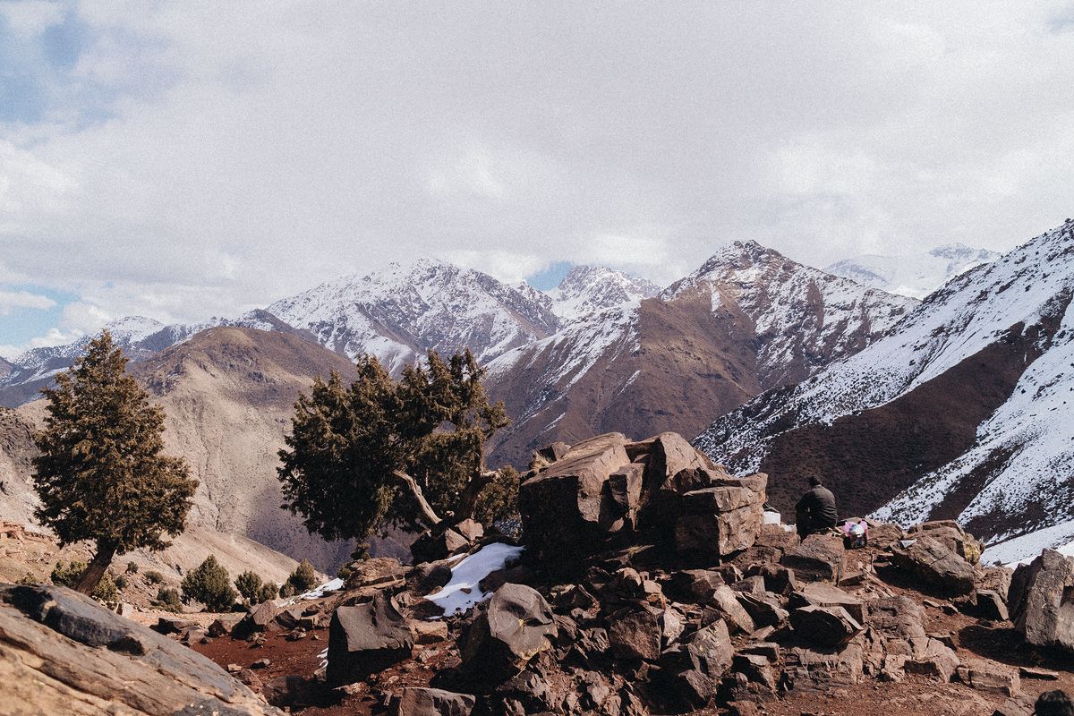 Snowy Atlas mountain peaks with rocky terrain and sparse trees in foreground In Imlil Valley during Moroccan Guides travel