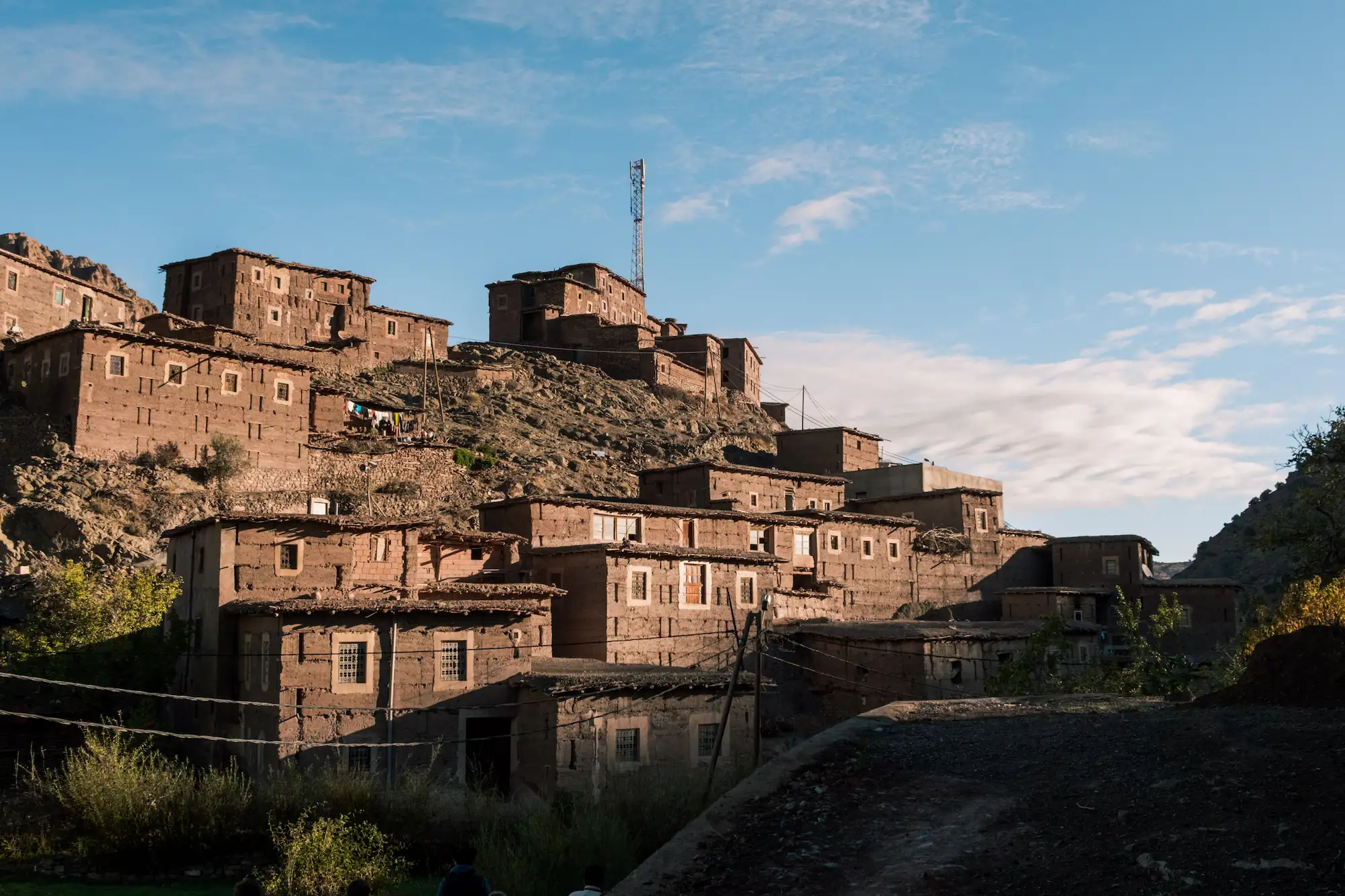 Rustic stone village with stacked buildings on rocky hillside under blue sky in the Ait Bougemz Valley in Morocco during a guided tour Moroccan Guides travel
