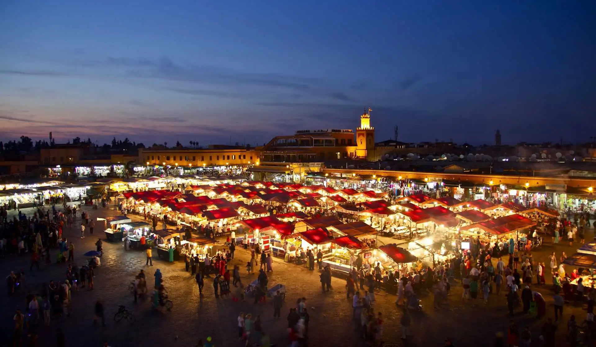 Jemaa el-Fnaa market in Marrakech at night, bustling with red-roofed stalls