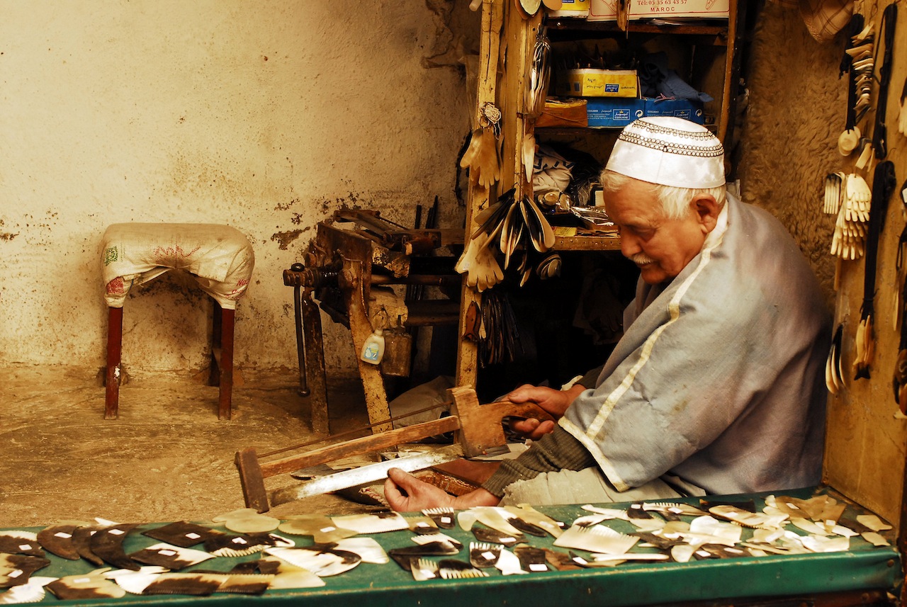 Elderly craftsman working on traditional combs in small workshop in the Medina in Fez Morocco during a guided tour Moroccan Guides travel